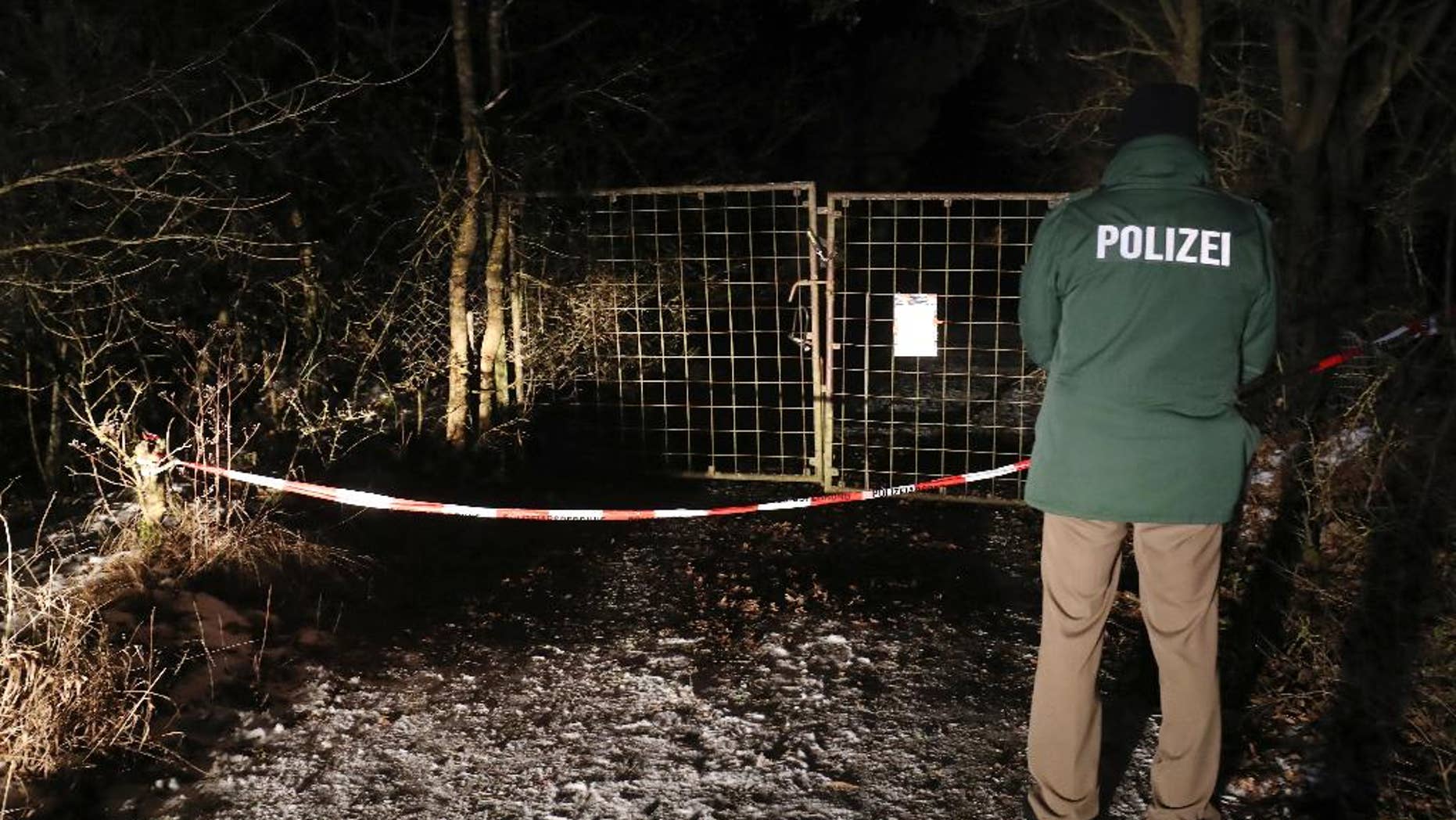 A police officer stands in front of a closed off entrance to a private ground near Arnstein, Germany, Sunday Jan. 29, 2017. Police in Germany say the bodies of six teenagers have been found dead in a garden house near the southern city of Wuerzburg. (Daniel Karmann/dpa via AP)
