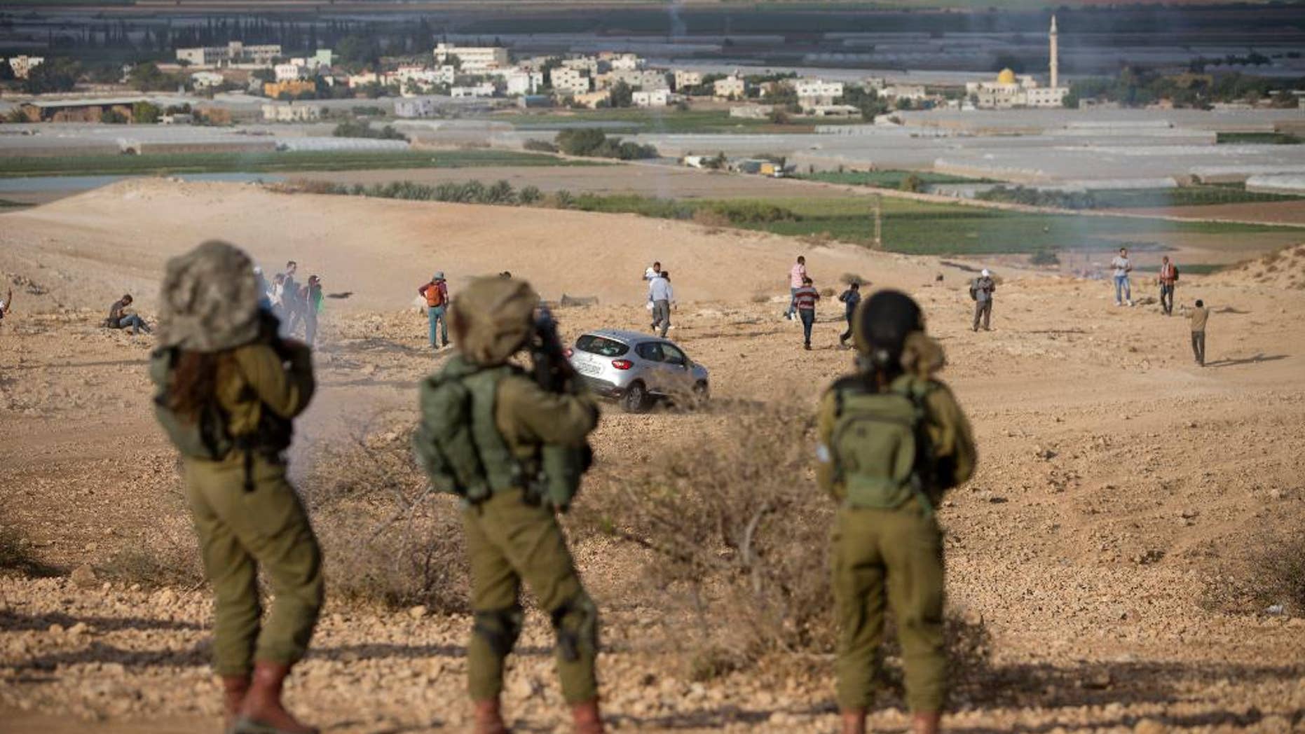 Palestinians and Israeli activists run away from a tear gas fired by Israeli soldiers during a demonstration against the construction of Jewish settlements in the Jordan Valley, in the West Bank, Thursday, Nov. 17, 2016. (AP Photo/Majdi Mohammed)