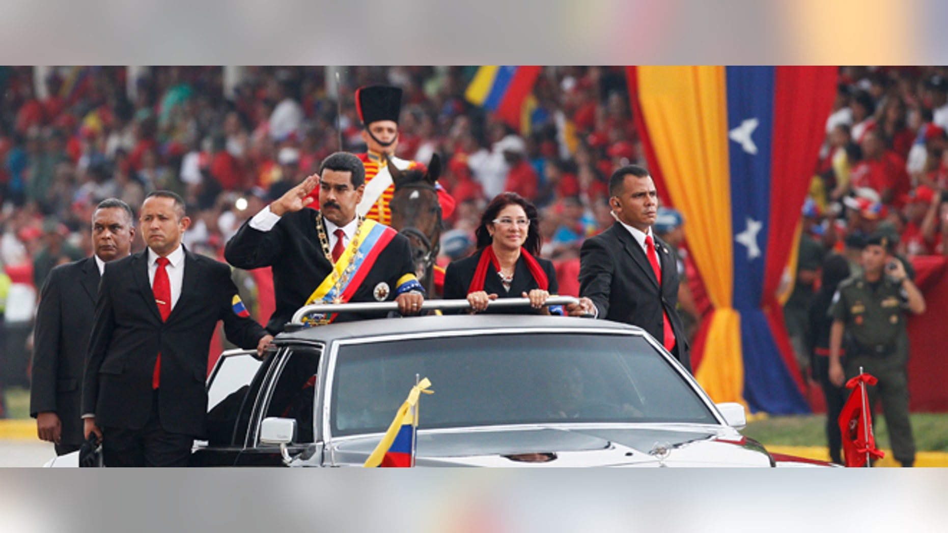 Venezuela's President Nicolas Maduro salutes from a vehicle, next to his companion Cilia Flores, during a military ceremony recognizing him as Commander-in-chief along the Paseo de Los Proceres, or "Promenade of the Forefathers" in Caracas, Venezuela, Friday, April, 19, 2013. Maduro, who has the support of the Chavista bases, needs all the momentum he can muster to consolidate control of a country struggling with shortages of food and medicines; chronic power outages; one of the world's highest homicide and kidnapping rates. (AP Photo/Ariana Cubillos)