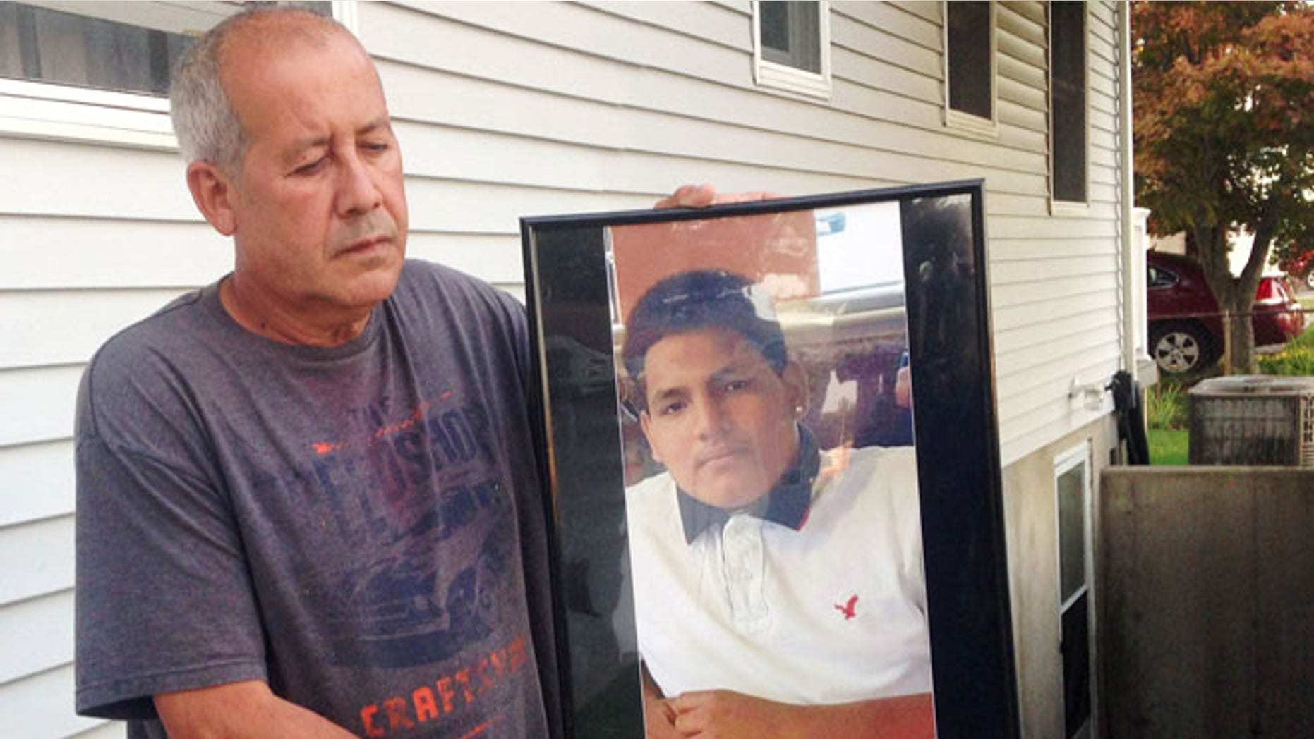 Abraham Chaparro holds a photograph of his murdered stepson Miguel Garcia-Moran, outside his home in Brentwood, N.Y.