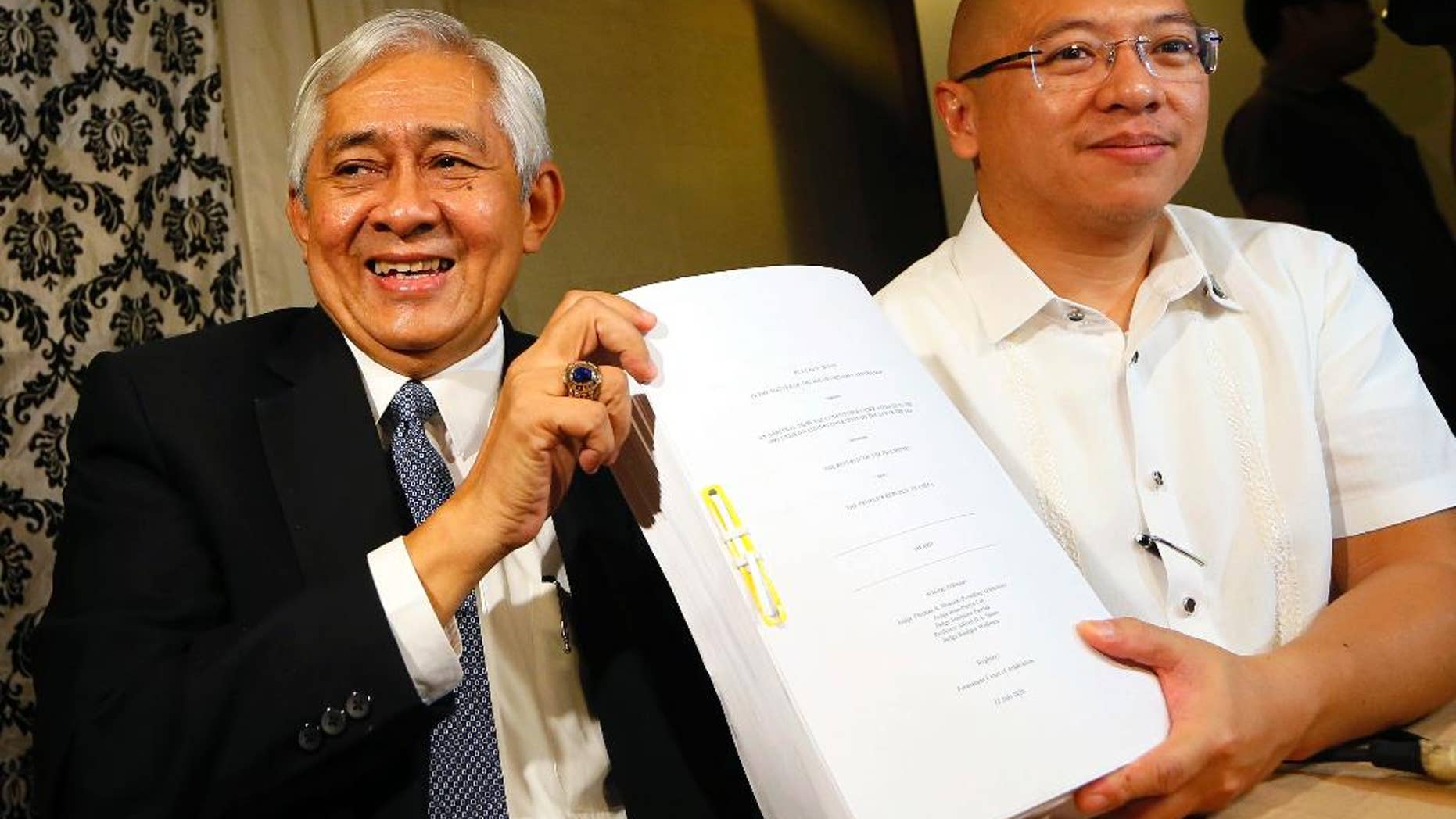 Associate Justice of the Supreme Court Francis Jardeleza, left, and former Solicitor General Florin Hilbay hold a photocopy of the Hague-based U.N. international arbitration tribunal ruling favoring the Philippines in its case against China on the dispute on South China Sea following a news conference Wednesday, July 13, 2016 in Manila, Philippines. The Permanent Court of Arbitration (PCA) issued its ruling Tuesday in The Hague in response to an arbitration case brought by the Philippines against China regarding the South China Sea, saying that any historic rights to resources that China may have had were wiped out if they are incompatible with exclusive economic zones established under a U.N. treaty. Jardeleza and Hilbay were members of the Philippine team who filed the case against China in The Hague. (AP Photo/Bullit Marquez)