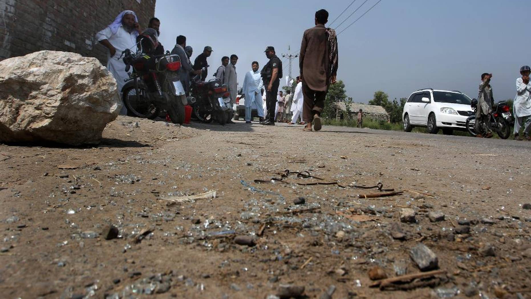 Pakistani police officers and local residents gather at the site of firing incident at Garhi Sohbat Khan on the outskirts of Peshawar, Pakistan, Sunday, Sept. 18, 2016. Two gunmen on a motorcycle killed three soldiers Sunday, police said. (AP Photo/Mohammad Sajjad)