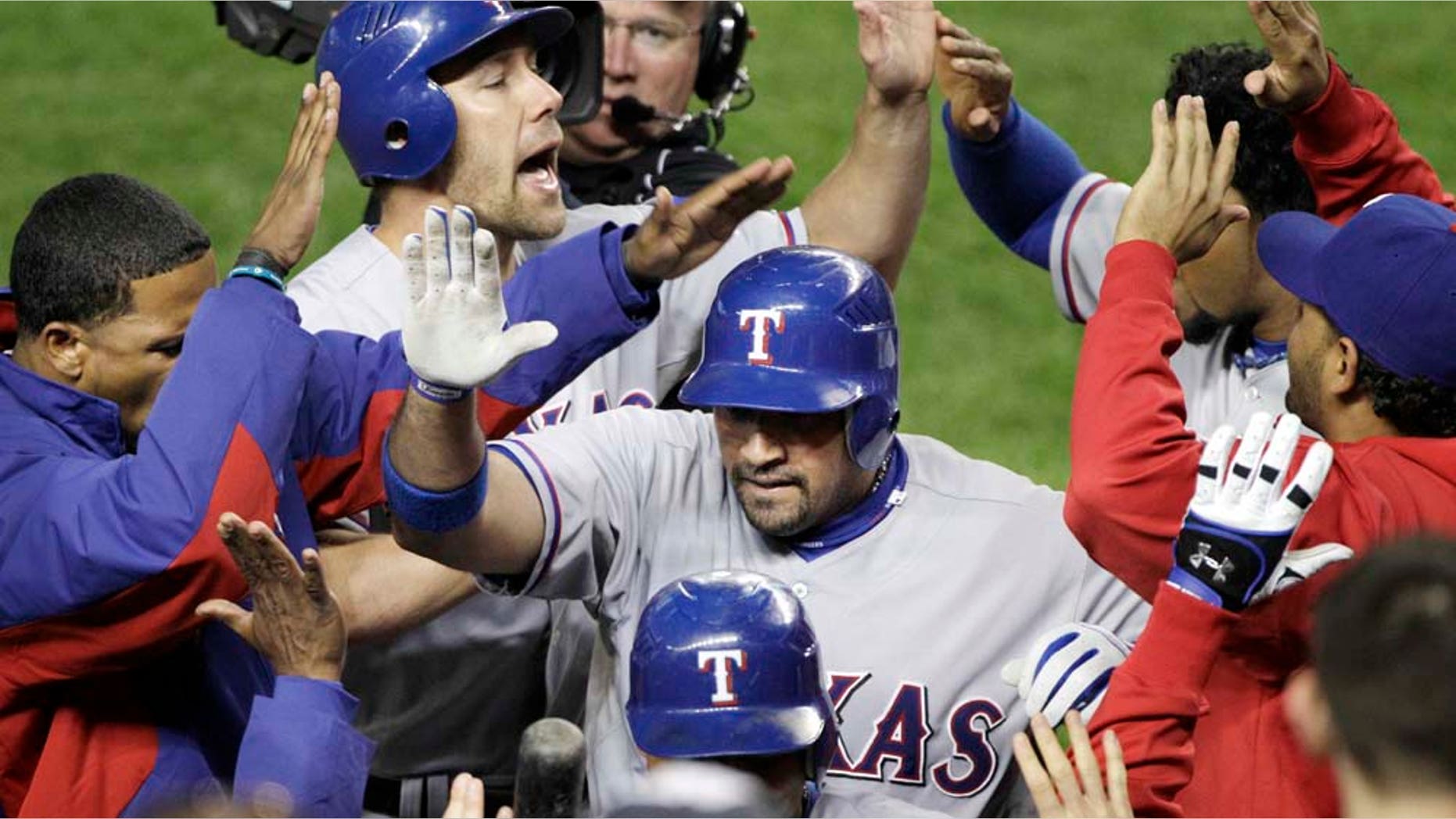 Texas Rangers' Bengie Molina, center, is greeted at the dugout after a three-run home run in the sixth inning of Game 4 of baseball's American League Championship Series against the New York Yankees Tuesday, Oct. 19, 2010, in New York. (AP Photo/Paul Sancya)