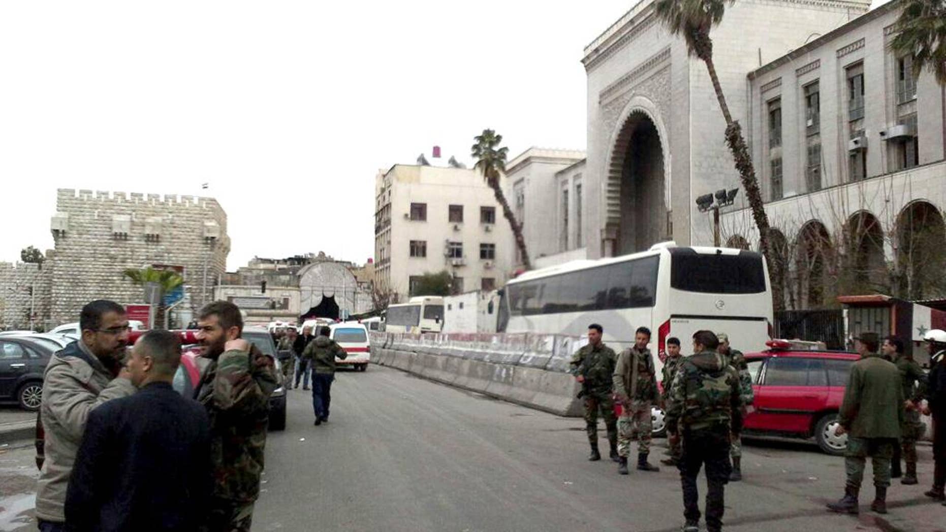 In this photo released by the Syrian official news agency SANA, Syrian security forces gather in front the main judicial building which attacked by a suicide bomber, in Damascus, Syria, Wednesday, March 15, 2017. (SANA via AP)
