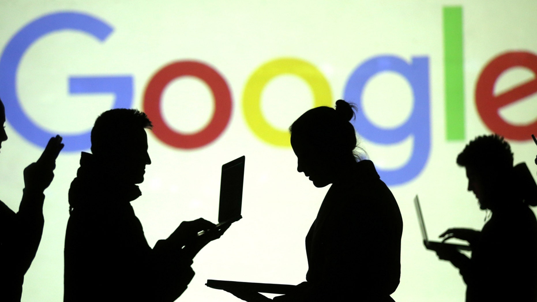 Silhouettes of laptop and mobile device users are seen next to a screen projection of Google logo in this picture illustration taken March 28, 2018. REUTERS/Dado Ruvic/Illustration - RC1F87EA23D0