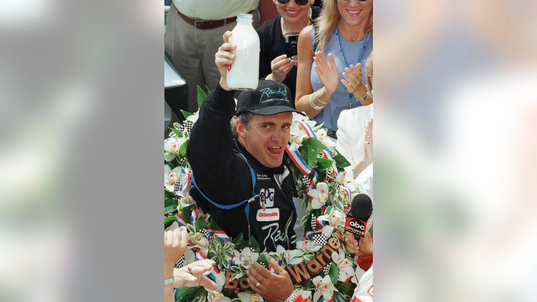 FILE - In this May 24, 1998 file photo, Indianapolis 500 winner Eddie Cheever hoists the traditional bottle of milk after winning the 82nd running of the race, in Indianapolis. (AP Photo/Michael Conroy, File)
