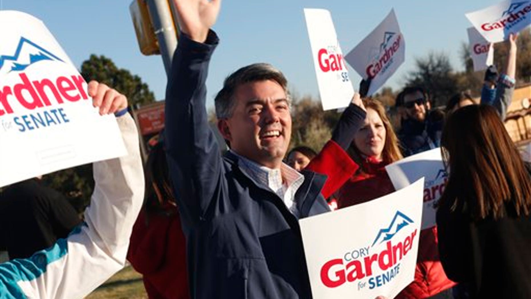 Cory Gardner, Republican candidate for the U.S. Senate seat in Colorado, joins supporters in waving placards on corner of major intersection in south Denver suburb of Centennial, Colo., early on Tuesday, Nov. 4, 2014. Gardner is facing Democratic incumbent U.S. Sen. Mark Udall in a pitched battle for the seat. (AP Photo/David Zalubowski)