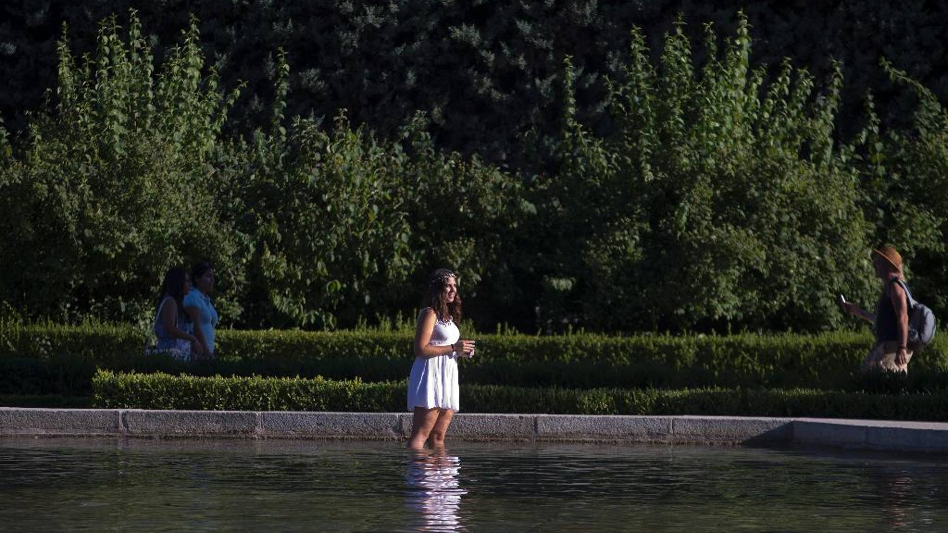 A woman cools off in a park pond in Madrid, Spain, Thursday, July 9, 2015. Spain has been in a heat wave for nearly two weeks, with temperatures reaching 40 C (104 F). The heatwave is expected to last around another week. (AP Photo/Paul White)