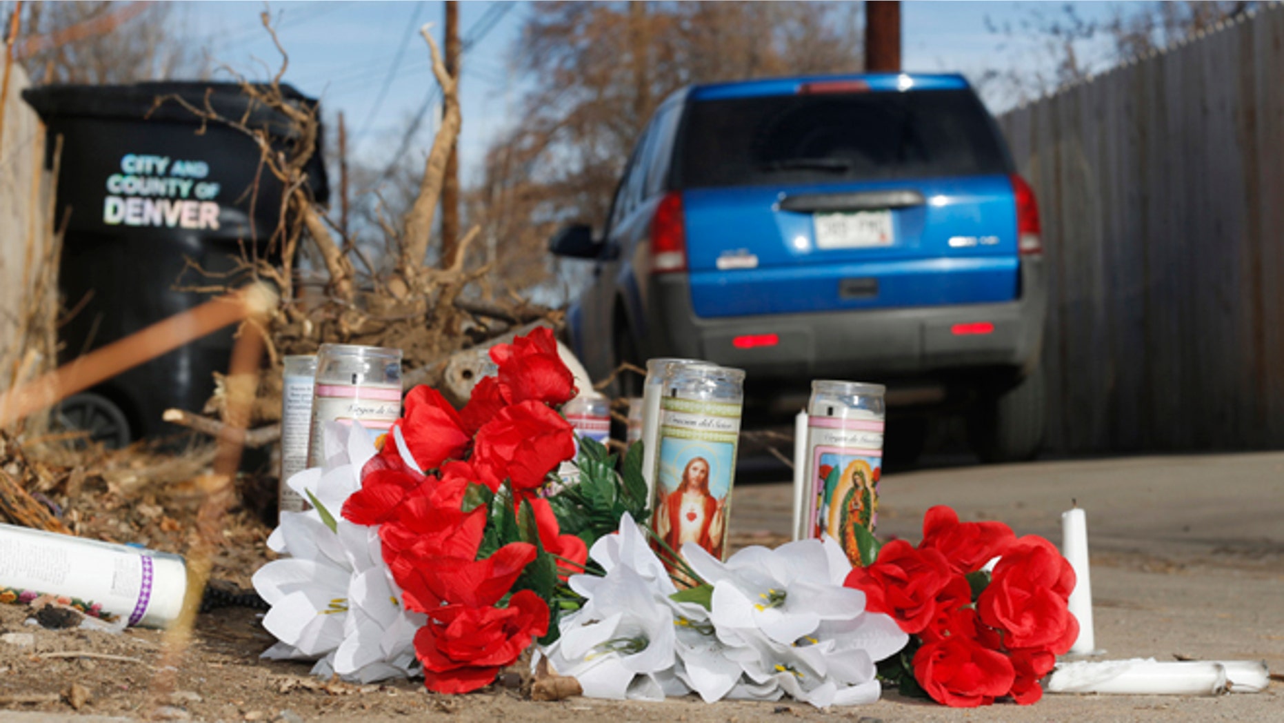 File--In this file photograph taken Tuesday, Jan. 27, 2015, a vehicle passes by the candles and bouquets left near the scene of a fatal police shooting in an alleyway in northeast Denver. A 17-year-old woman was fatally shot by police after she allegedly hit and injured an officer while driving a stolen vehicle early Monday, Jan. 26, in a northeast Denver alleyway. On Friday, June 5, 2015, Denver District Attorney Mitch Morrissey issued a statement saying that the two Denver Police officers involved in the shooting will not face criminal charges. (AP Photo/David Zalubowski, file)