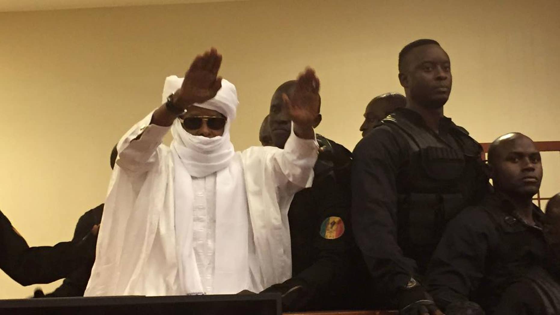 FILE-In this file photo taken on Monday, May 30, 2016, Chad's former dictator Hissene Habre raises his hands after sentencing during court proceedings in Dakar, Senegal. A tribunal ordered Chad's ex-dictator Hissene Habre on Friday, July 29, 2016, to pay more than 4,700 victims at least $17,000 each for abuses suffered during his time in power. (AP Photo/Carley Petesch,File)