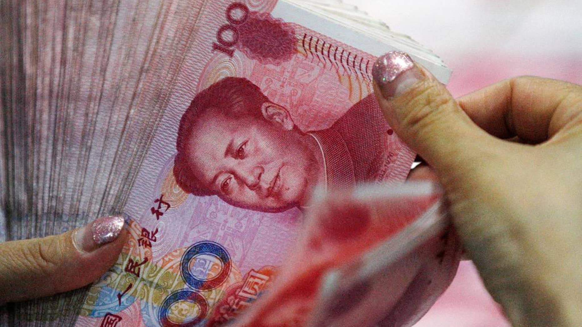 In this Tuesday, Aug. 11, 2015 photo, a bank clerk counts Chinese currency notes at a bank outlet in Huaibei in central China's Anhui province. China's unexpected devaluation of its currency in August raised fears that the world's second-largest economy was slowing more than anyone had thought. (Chinatopix via AP, File) CHINA OUT