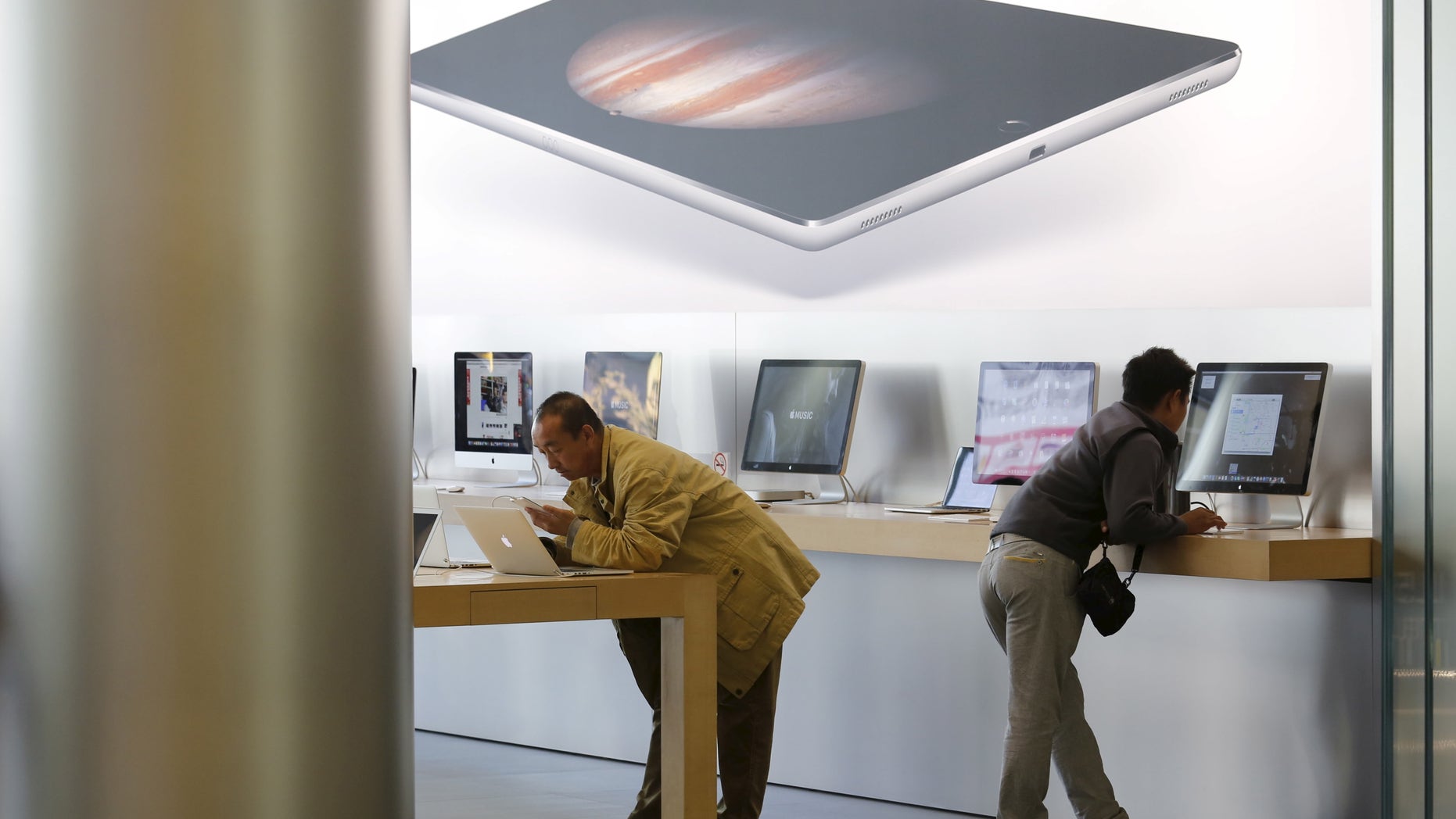 Men try apple's MacBook laptops at an apple store in Beijing. (REUTERS/Kim Kyung-Hoon)