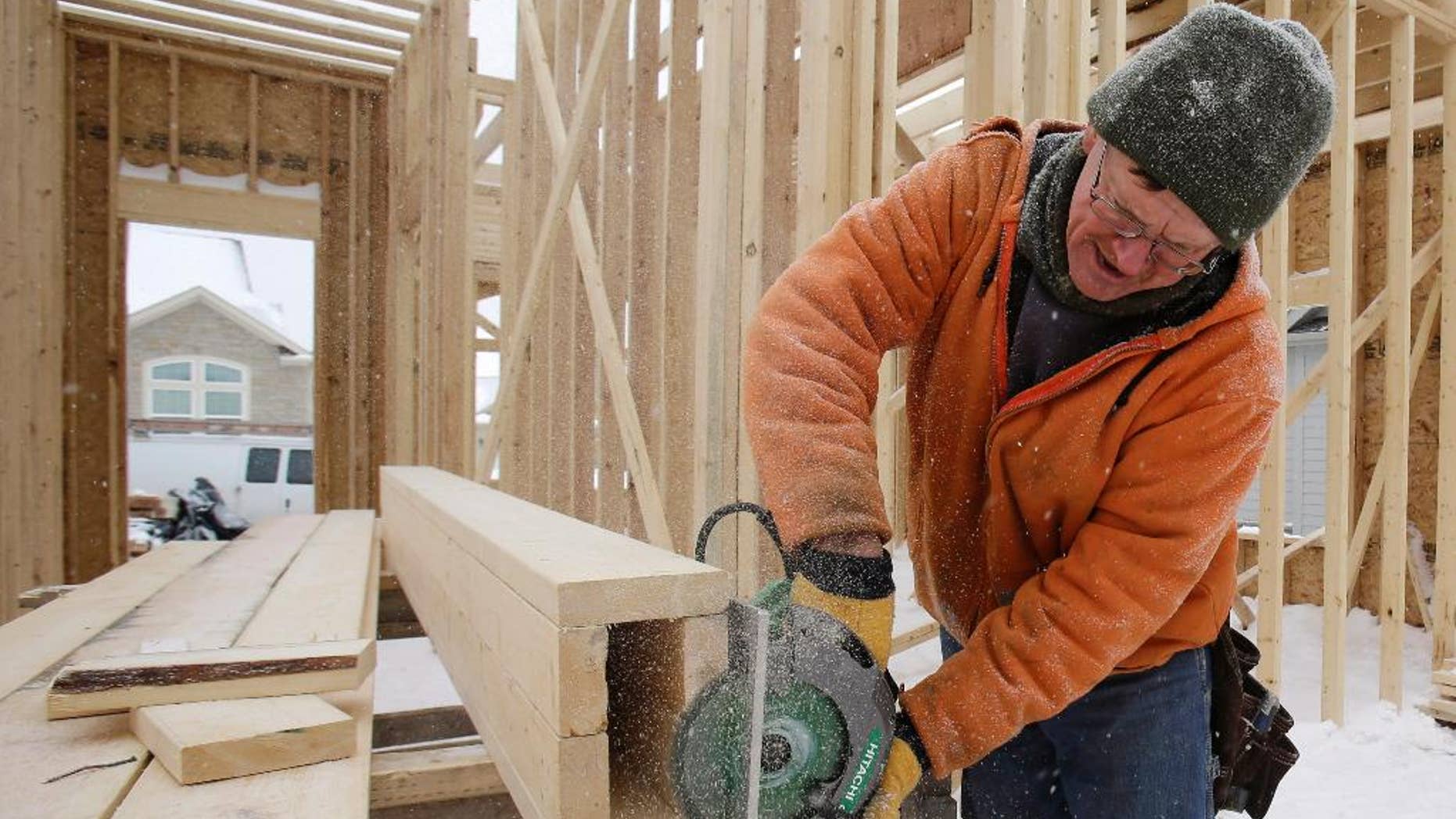 In this Wednesday, Feb. 18, 2015 photo, carpenter Joe Tominc cuts wood for a post on a home under construction in Pepper Pike, Ohio. The Commerce Department reports on U.S. construction spending in January on Monday, March 2, 2015. (AP Photo/Tony Dejak)