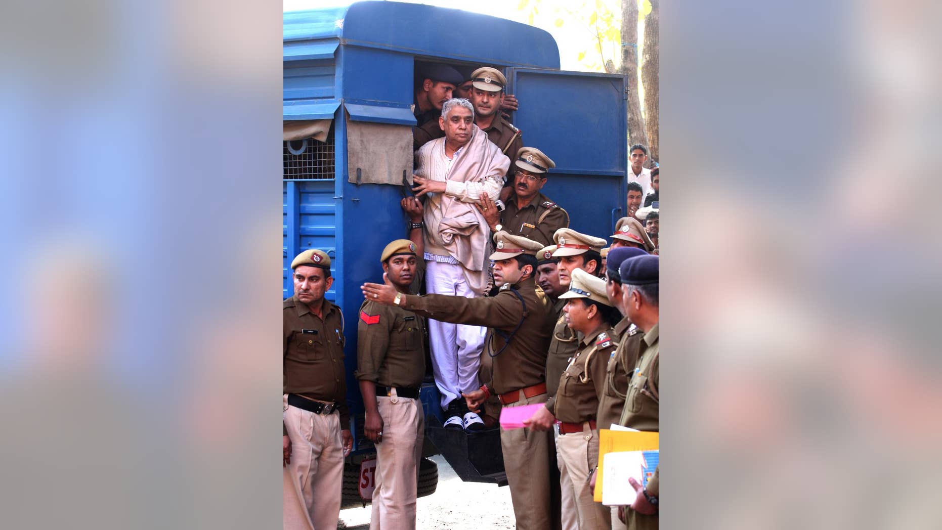 Controversial religious leader Sant Rampal stands by the door of a police van as he is brought to a court, surrounded by police personnel in Chandigarh, India, Thursday, Nov. 20, 2014. Indian police arrested the 63-year-old self-styled Hindu guru at his sprawling ashram in the northern part of the country, ending a days-long standoff in which six people died and hundreds were injured. He is wanted for questioning in a 2006 murder case, but has repeatedly ignored orders to appear in court. (AP Photo/Kapil Sethi)