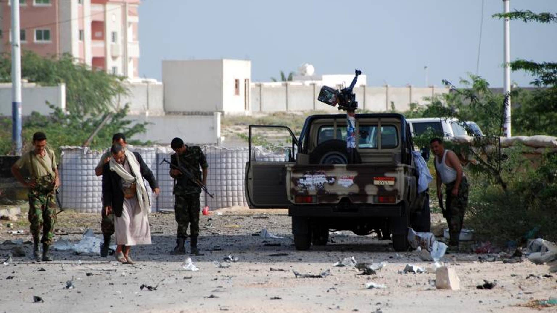 Yemeni security forces are seen along a main road littered with debris after a suicide bomber blew up a vehicle outside a presidential palace in Mukalla on February 25, 2012