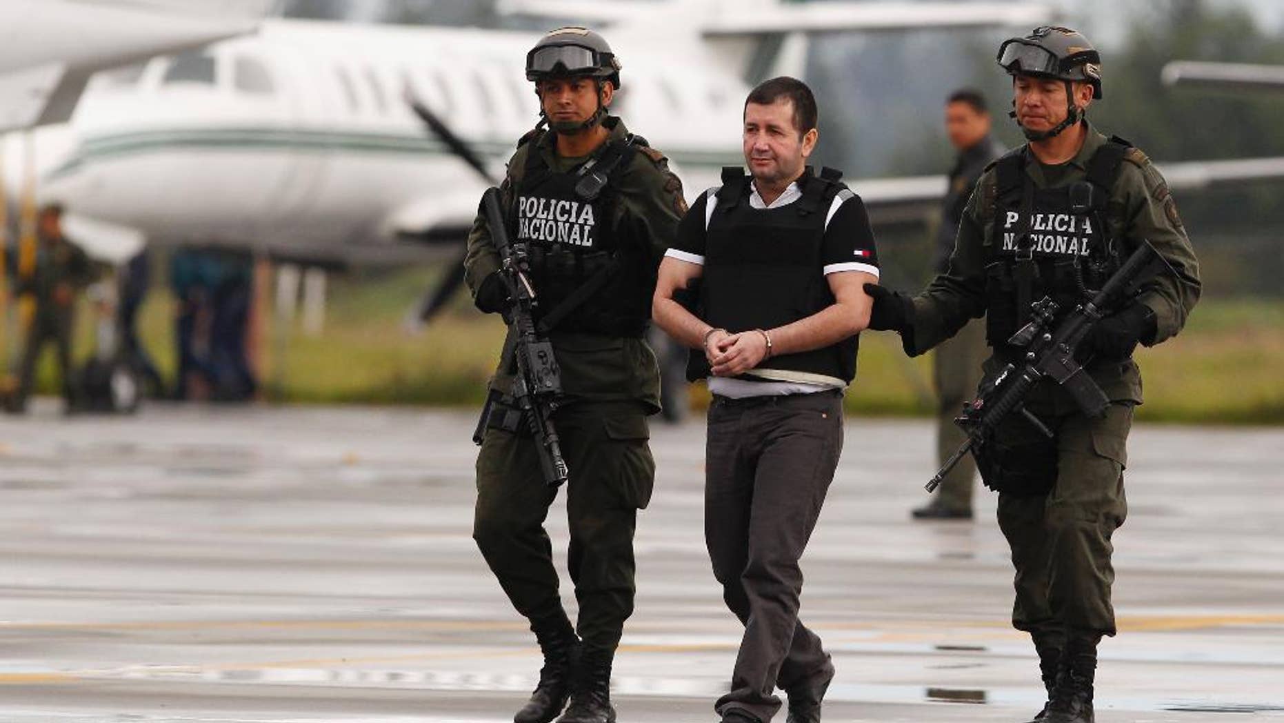 FILE - In this Tuesday July 9, 2013 file photo, Daniel Barrera, center, is escorted by police to a waiting car prior to his extradition to the U.S. from the counter-narcotics base in Bogota, Colombia. Known as "El Loco," Spanish for "The Madman," Barrera is scheduled to be sentenced Mondauy, July 25, 2016, and faces a mandatory minimum of 10 years in prison and up to life after pleading guilty to a drug trafficking charge. (AP Photo/Fernando Vergara, File)