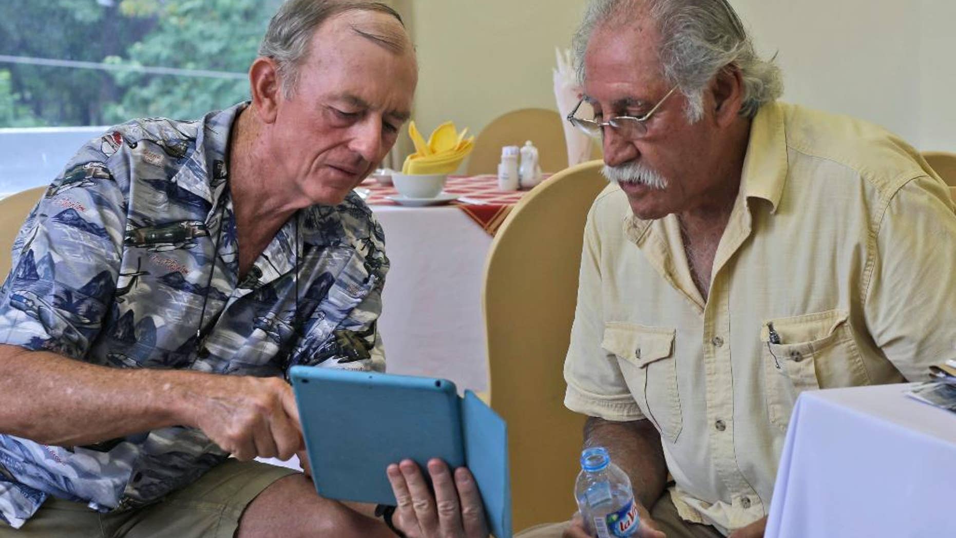 In this Tuesday, April 28, 2015 photo, former U.S. Marines Sgt. Kevin Maloney, left, of Hollywood, Florida, and Master Gunnery Sgt. Juan Valdez, of Oceanside, Calif., browse some photos on Maloney's tablet in Ho Chi Minh City, Vietnam. On the 40th anniversary of the fall of Saigon, 13 Marines who were there that day returned to dedicate a plague to their two fallen comrades at the site of the old embassy, which is now the U.S. Consulate. (AP Photo/Dita Alangkara)