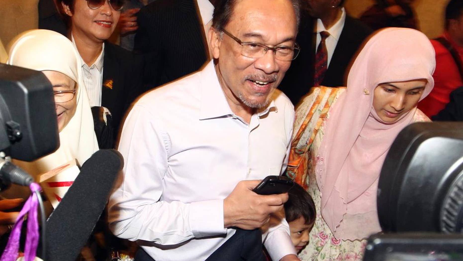 FILE - In this Tuesday, Feb. 10, 2015 file photo, Malaysian opposition leader Anwar Ibrahim, center, arrives at court house in Putrajaya, Malaysia. Less than a week after Anwar was jailed for sodomy, his lawyers said Monday, Feb. 16, he faces a serious health risk, being kept in a bare cell with just a 2-inch-thick foam mattress on the floor, a bucket for bathing and a squat toilet. Anwar began a five-year prison sentence last Tuesday after the country's top court turned down his final appeal, ruling there was overwhelming evidence that he had sodomized a former male aide. (AP Photo/File) MALAYSIA OUT