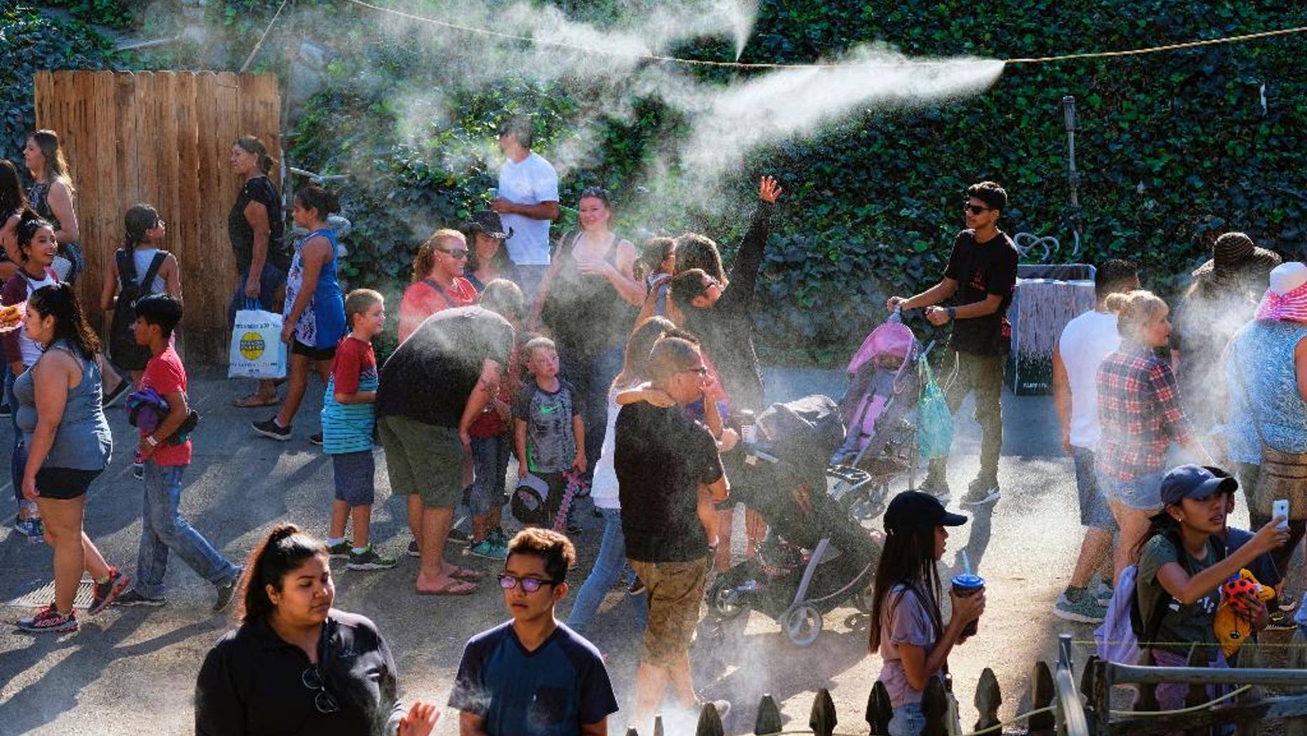 In this Saturday, Sept. 24, 2016 photo, visitors to the Los Angeles County fair cool off under outdoor misters in Pomona, Calif. Californians braced Monday, Sept. 26 for another hot autumn day as forecasters warned of soaring temperatures and potential wildfires due to hot, dry and windy conditions. (AP Photo/Richard Vogel)
