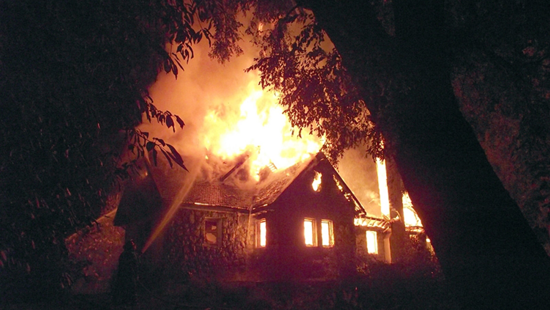 A firefighter, left, works to extinguish the flames of the home of a wealthy landowner in Temuco, Chile, Friday, Jan. 4, 2013. The elderly couple, Werner Luchsinger, 75, and wife wife Vivian McKay, whose family's vast landholdings have long been targeted by Mapuche Indians in southern Chile were killed in the arson attack early Friday while trying to defend their home. Chile's president quickly flew to the scene and announced new security measures, including the application of Chile's tough anti-terrorism law and the creation of a special police anti-terror unit backed by Chile's military. (Hector Andrade/Agenciauno)