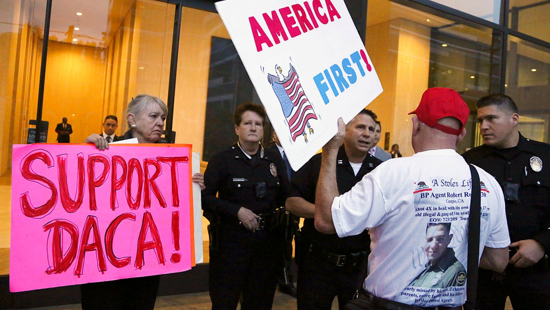 A supporter of President Donald Trump challenges police officers and a Deferred Action for Childhood Arrivals (DACA) program during a rally outside the office of California Democratic Sen. Dianne Feinstein in Los Angeles, Wednesday, Jan. 3, 2018. (AP Photo/Reed Saxon)