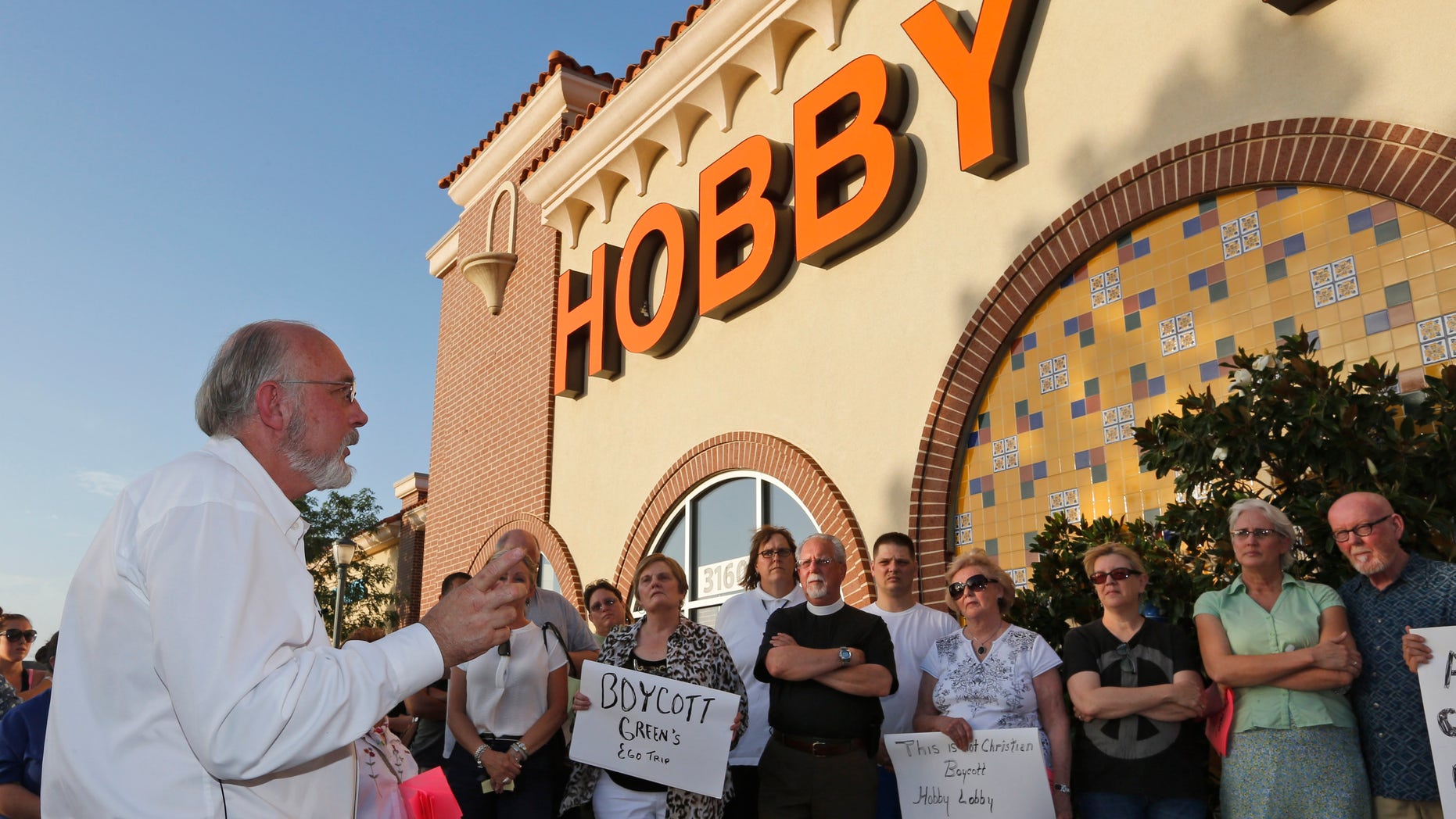 Rev. Bruce Prescott, left, speaks during a vigil outside a Hobby Lobby store in Edmond, Okla., Monday, June 30, 2014.