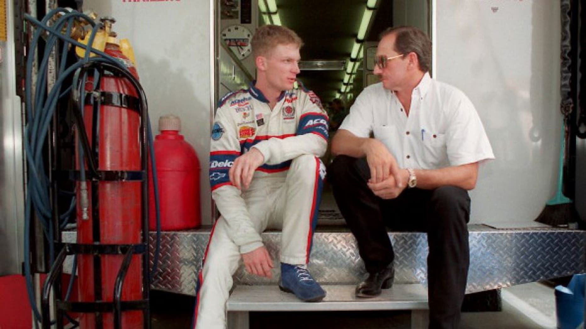 Dale Earnhardt Jr. and Dale Earnhardt Sr., sit on the back of a transporter discussing Earnhardt Jr.'s preparation for Carquest 300 Grand National qualifications on May 21, 1998 in Concord, North Carolina. (Photo by Jeff Siner/Charlotte Observer/MCT via Getty Images)