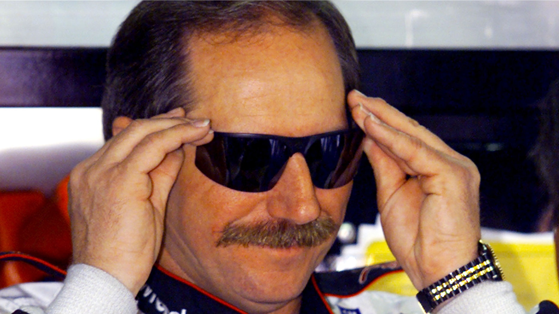 Late NASCAR driver Dale Earnhardt adjusts his glasses as he prepares to practice for the upcoming Daytona 500 at the Daytona International Speedway.