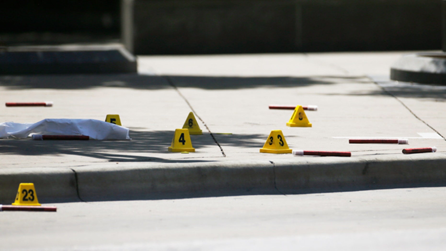 Markers litter the sidewalk as FBI investigators look over the crime scene in Dallas, Texas, U.S. July 8, 2016 following a Thursday night shooting incident that killed five police officers. REUTERS/Carlo Allegri - RTX2KE0D