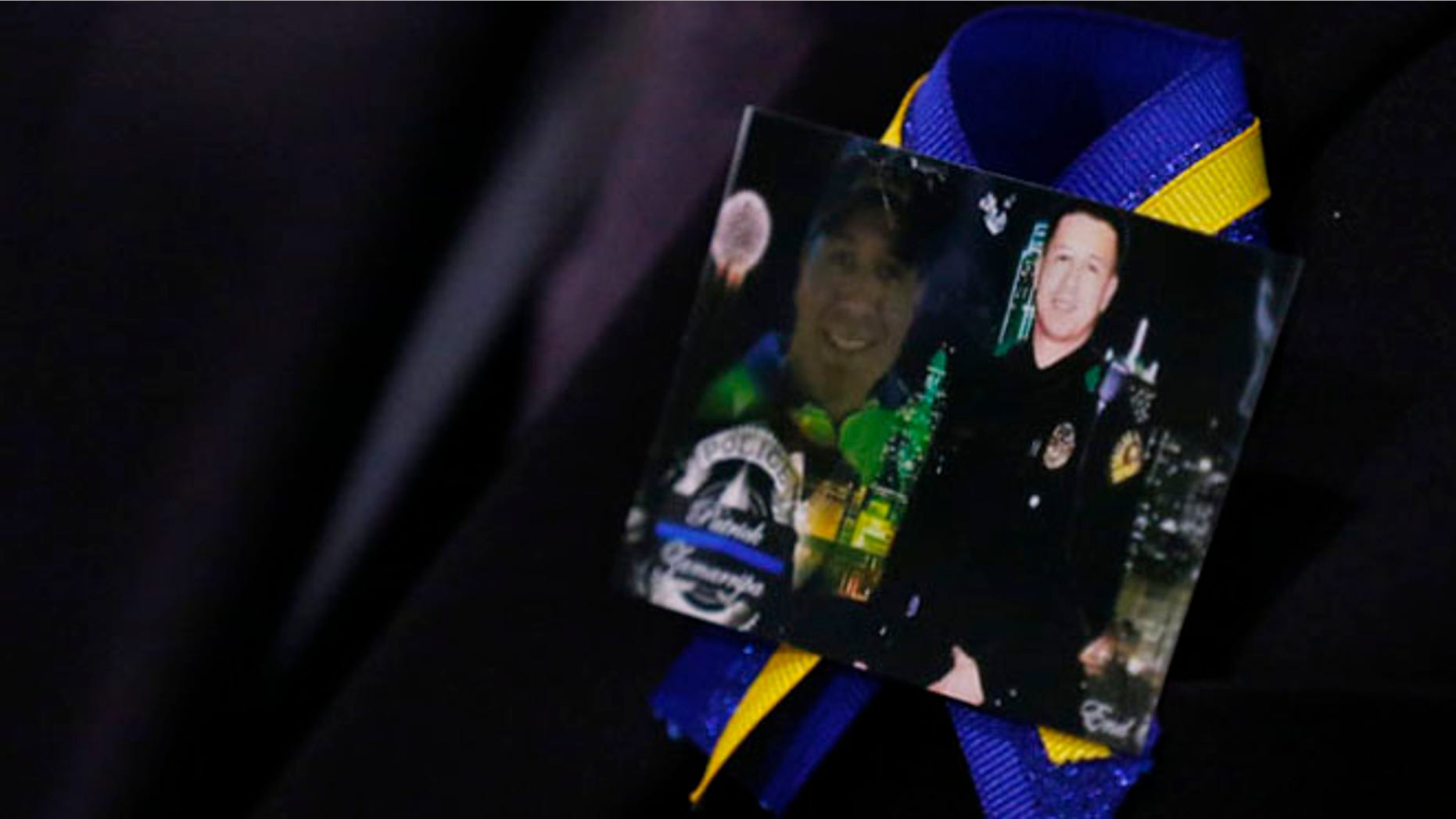 A family member wears a ribbon with photos of Patrick Zamarripa during a funeral service for Dallas police officer Patrick Zamarripa on Saturday, July 16, 2016 at Wilkerson-Greines Athletic Center in Fort Worth, Texas. Zamarripa was one of the five officers killed July 7 by a lone gunman during a march to protest recent fatal shootings of black men in Minnesota and Louisiana by police. (Ashley Landis/The Dallas Morning News via AP, Pool)