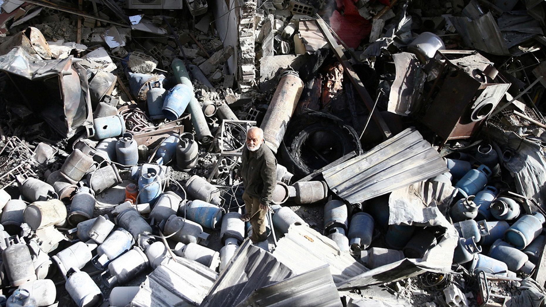 A man stands on the rubble of damaged buildings after an airstrike on the rebel-held town of Mesraba in the eastern Damascus suburb of Ghouta, Syria, November 26, 2017.