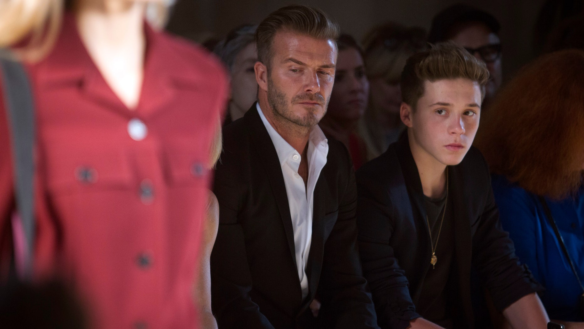 David Beckham and his son Brooklyn Beckham watch a model present a creation during the Victoria Beckham Spring/Summer 2015 collection during New York Fashion Week in the Manhattan borough of New York September 7, 2014. REUTERS/Carlo Allegri (UNITED STATES - Tags: FASHION ENTERTAINMENT SPORT SOCCER) - RTR459GR