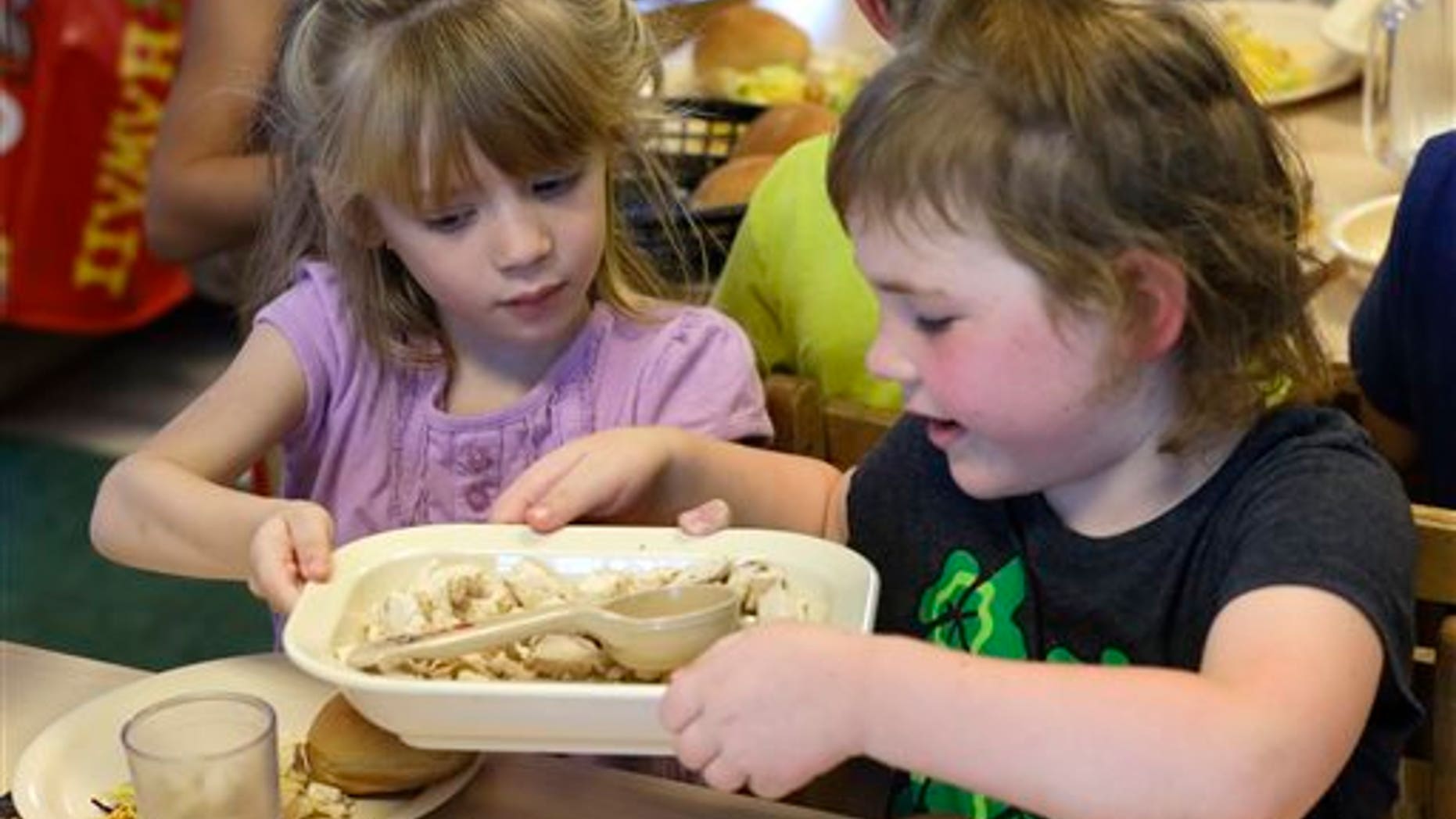 FILE -- June 24, 2015: Rebekah Webb, left, shares a family-style meal with Zoe Turner during lunch with other five-year-olds at the Olathe Family YMCA in Olathe, Kan. (AP Photo/Orlin Wagner)