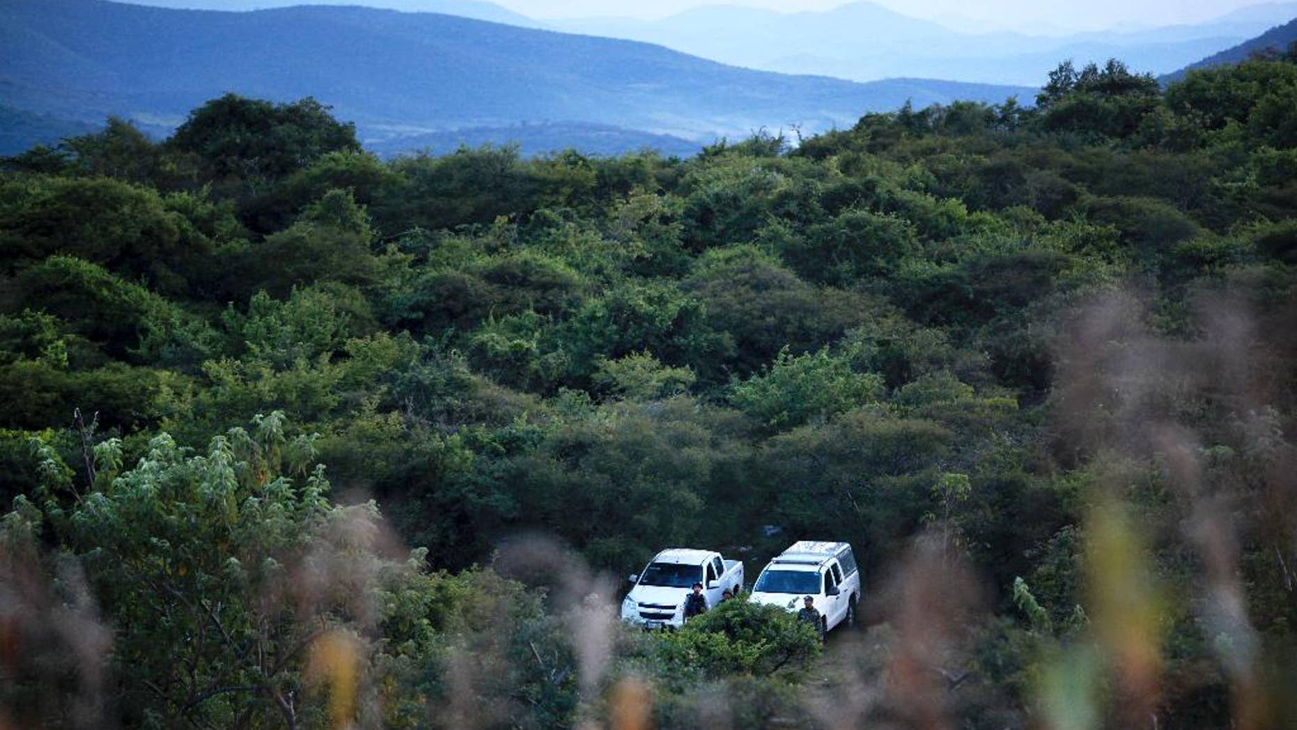 Mexican navy marines and officers belonging to the Attorney General's Office guard the area where new clandestine mass graves were found near the town of La Joya, on the ouskisrts of Iguala, Mexico, Thursday Oct. 9, 2014. Two weeks after 43 students disappeared in a confrontation with police in rural southern Mexico, Attorney General Jesus Murillo Karam announced that suspects had led investigators to four new mass graves near the southern city of Iguala where authorities unearthed 28 badly burned bodies last weekend. (AP Photo/Felix Marquez)