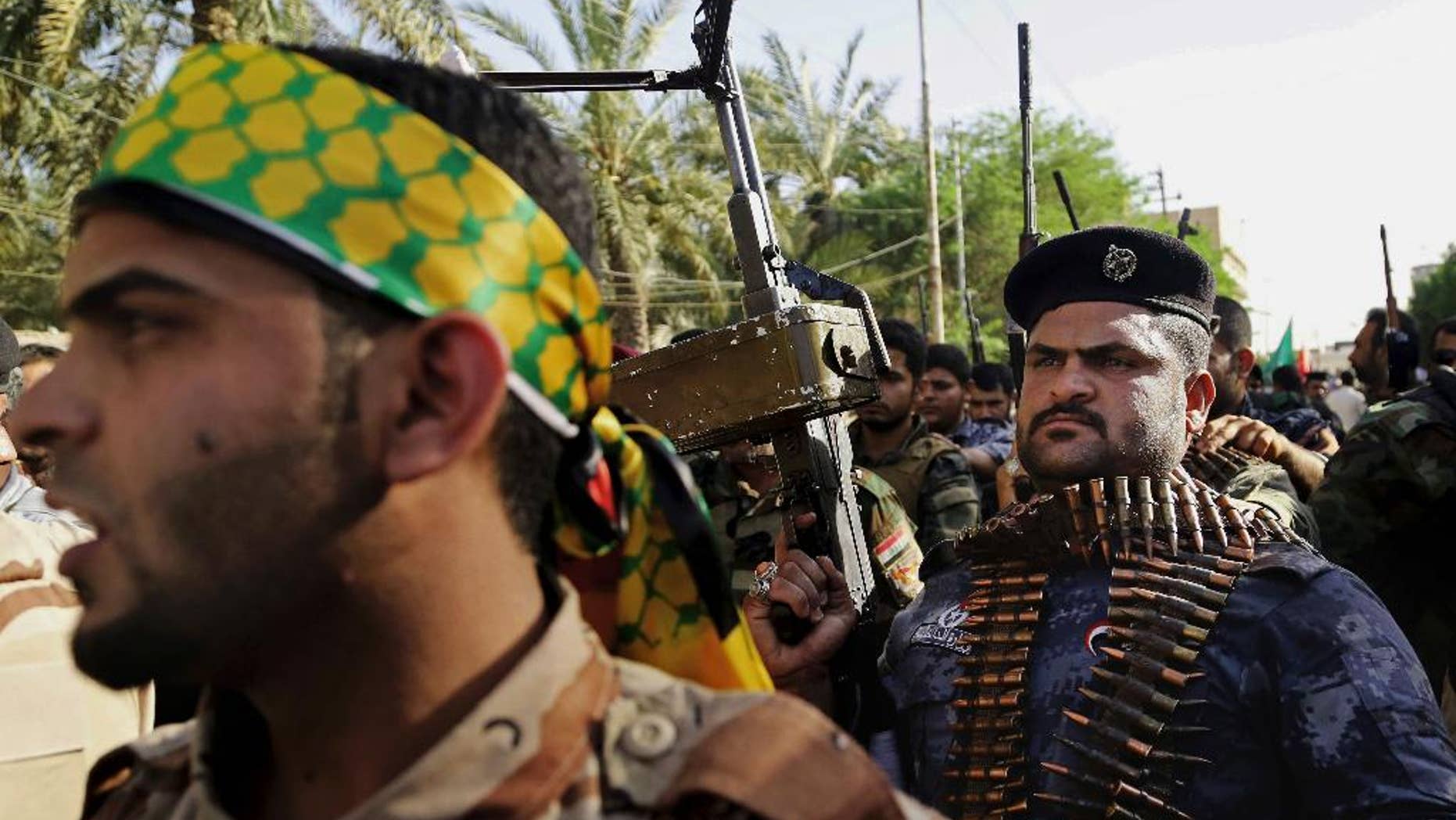 FILE - In this Monday, June 16, 2014 file photo, Shiite tribal fighters raise their weapons and chant slogans against the al-Qaida-inspired Islamic State of Iraq and the Levant, who now call themselves the Islamic State, in Basra, Iraq. Iran and the United States share a common enemy in the Islamic State militant group, but a deep-seated lack of trust has so far kept the longtime foes from publicly joining hands in a coalition to defeat the extremists. Their inability to work together complicates efforts to beat back the extremists that both Washington and Tehran see as a threat, and has left Iraq’s new government - which considers both countries allies - scratching its head as it tries to tackle the most serious threat to its stability since American troops left in 2011. (AP Photo/ Nabil Al-Jurani, File)