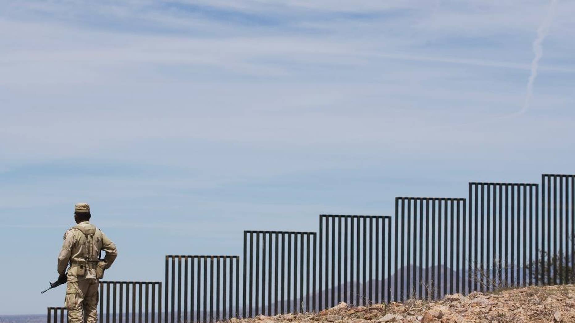 FILE - In this April 1, 2008 file photo, a Mexican soldier patrols along the U.S.-Mexico border wall on the outskirts of Nogales, Mexico. The billions of dollars in U.S. remittances that Donald Trump is threatening to block to force Mexico to pay for a border wall are a financial lifeline for the Latin American country’s economy and millions of individuals who are supported by relatives up north. (AP Photo/Guillermo Arias, File)