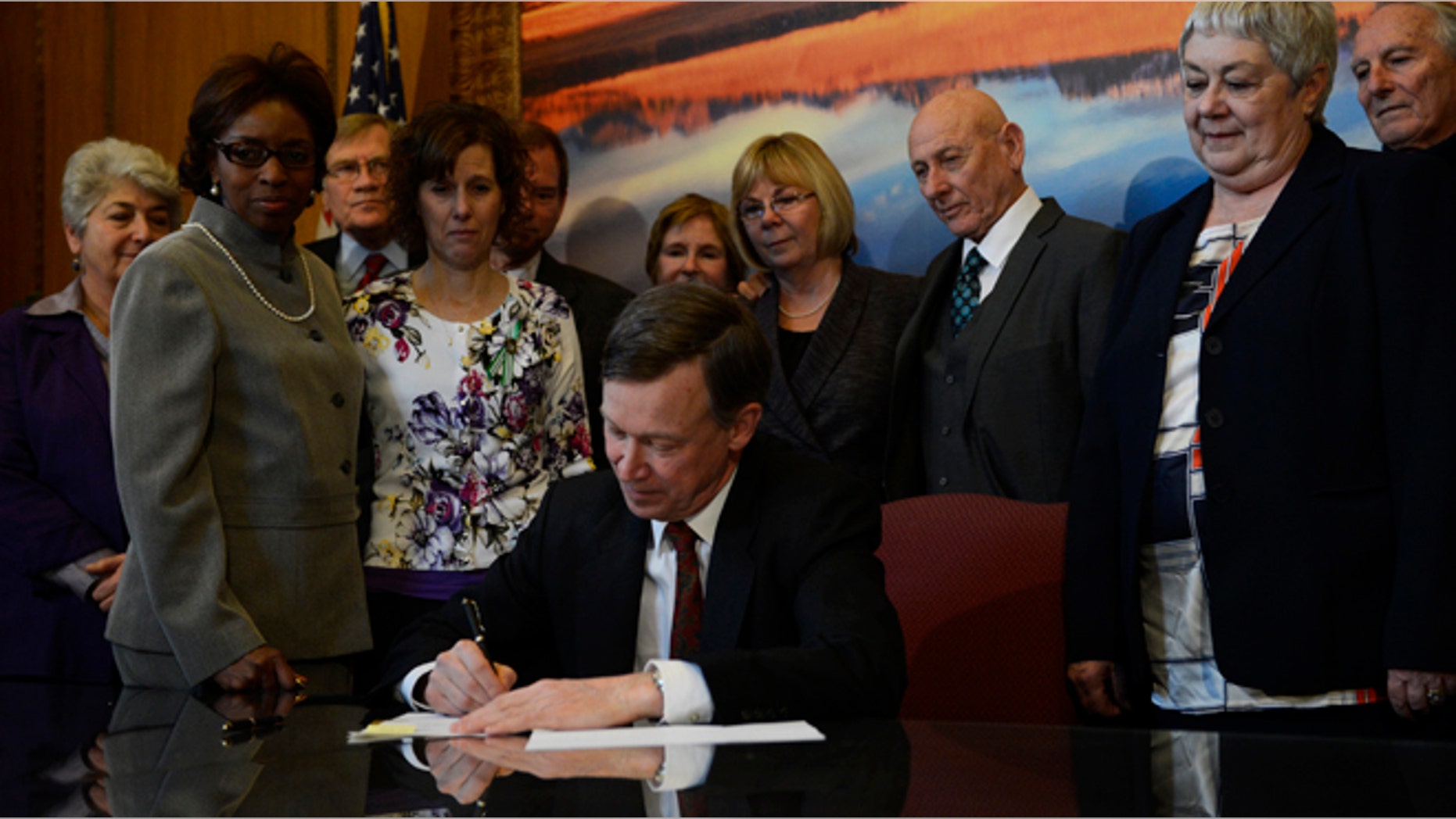 FILE: March, 20, 2013: Colorado Governor John Hickenlooper signs gun control bills into law in his office at the state capitol in Denver, Colo.