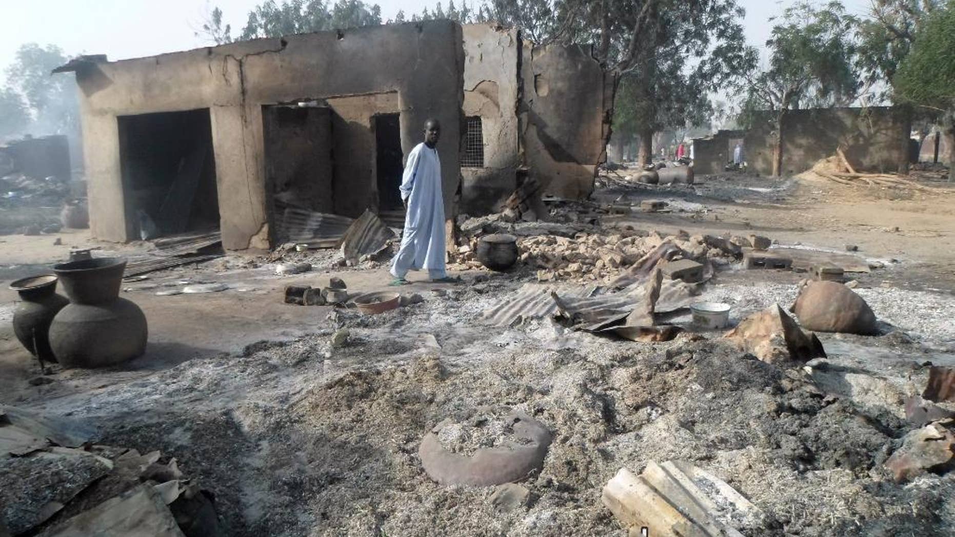 FILE - In this Sunday Jan. 31, 2016 file photo, a man walks past burnt out houses following an attack by Boko Haram in Dalori village near Maiduguri, Nigeria. Abubakar Shekau says he still leads Boko Haram, exposing the biggest rift yet among Nigeria’s Islamic insurgents and possibly paving the way for a break from the Islamic State group. The Islamic State on Wednesday, Aug. 3, 2016 announced that Abu Musab al-Barnawi is the new leader of its so-called West Africa province. But an audio speech Thursday purporting to be from Shekau criticizes al-Barnawi as “an infidel.” (AP Photo/Jossy Ola, File)