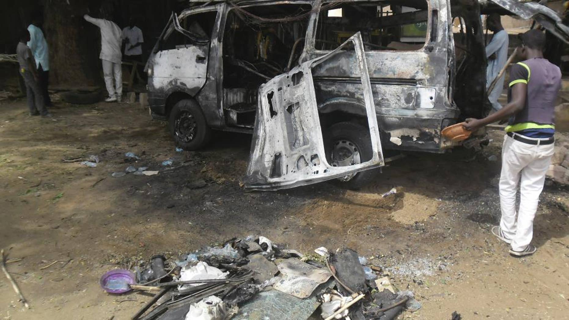 FILE- In this Tuesday, Feb. 24, 2015 photo, Men inspect a bus following an explosion in one of the recent suicide bomb explosion in a bus station in Potiskum, Nigeria. A teenage suicide bomber blew herself up and killed seven other people Saturday, May 16, 2015, outside a bustling bus station in the northeast Nigerian town of Damaturu, the state medical director said of the latest in a string of attacks this week by Nigeria's home-grown Boko Haram extremists. Thirty-three people were seriously injured and are being treated at the hospital, said Yobe state's medical director Garba Musa Fika. (AP Photo/Adamu Adamu file )