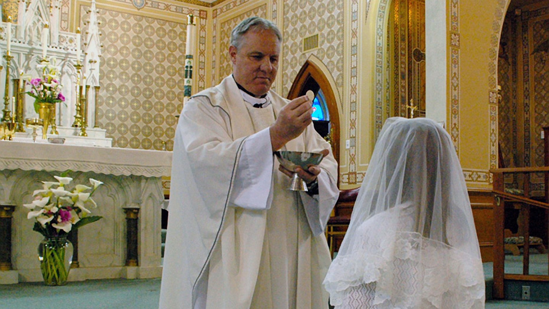 FILE - In this May 2012 file photo provided by Lynn Enemark shows the Rev. Eric Freed giving First Communion in St. Bernard Catholic Church in Eureka, Calif. Free was found slain New Year's Day in the rectory of the church. A funeral is planned late Monday morning, Jan. 6, 2014 for Rev. Eric Freed, who was beaten to death in the church rectory last week. A suspect arrested in the slaying, Gary Bullock, is scheduled to be arraigned in the afternoon. (AP Photo/Lynn Enemark, File) NO SALES