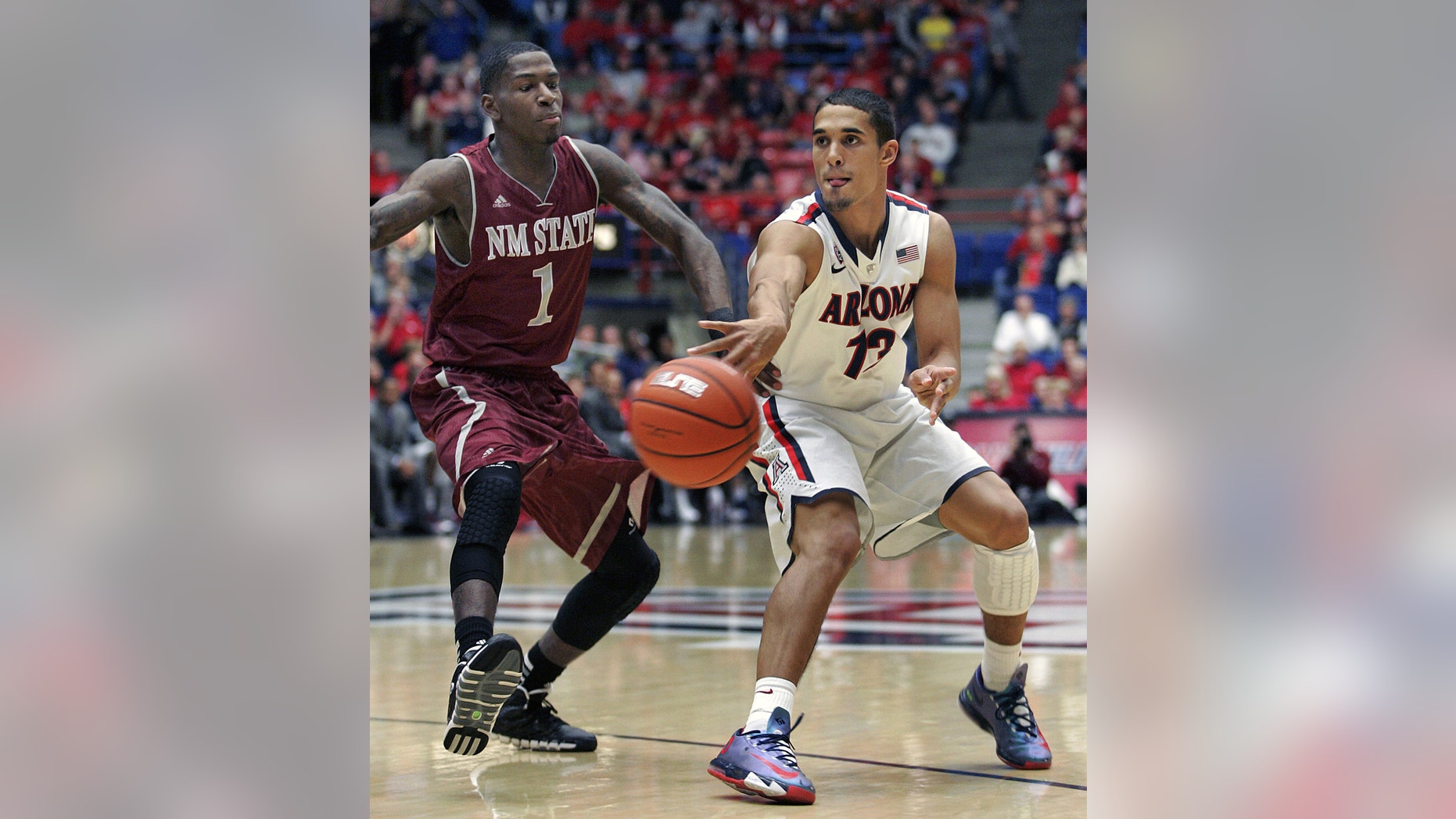 Arizona's Nick Johnson (13) passes the ball in front of New Mexico States' DK Eldridge (1) in the first half of an NCAA college basketball game on Wednesday, Dec. 11, 2013 in Tucson, Ariz. (AP Photo/John MIller)