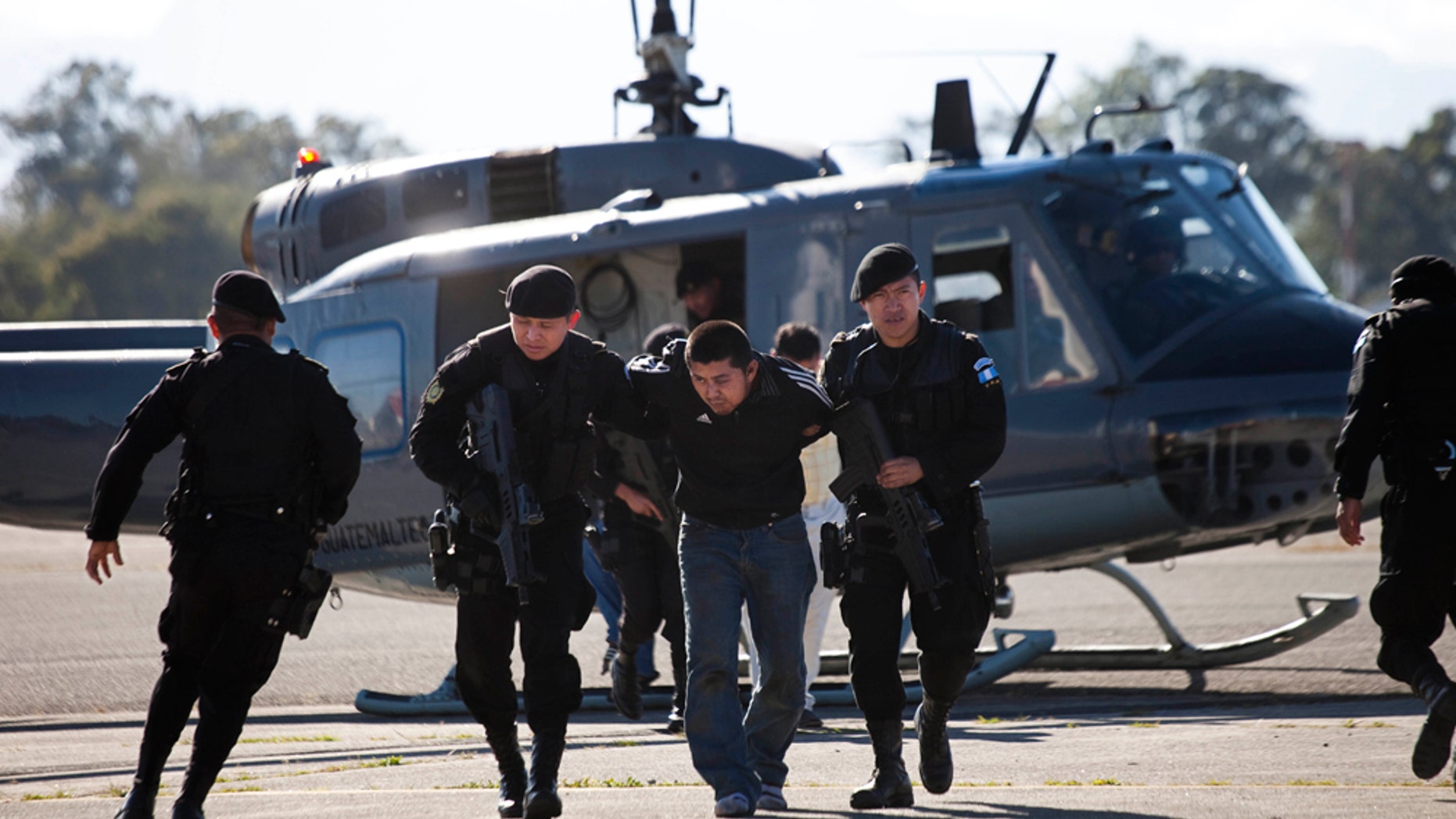 Police officers escort a man, third from left, suspected to participate in an attack to a jail, upon his arrival to Guatemala City, Thursday, Dec. 9, 2010. Guatemalan authorities said 15 men stormed into a jail armed with assault rifles and a grenade launcher Wednesday and freed Elmer Aroldo Zelada, a man accused of killing a professional soccer player. Guatemala Interior Minister Carlos Menocal said authorities believe the group is affiliated with the Zetas, a Mexican drug cartel. (AP Photo/Rodrigo Abd)