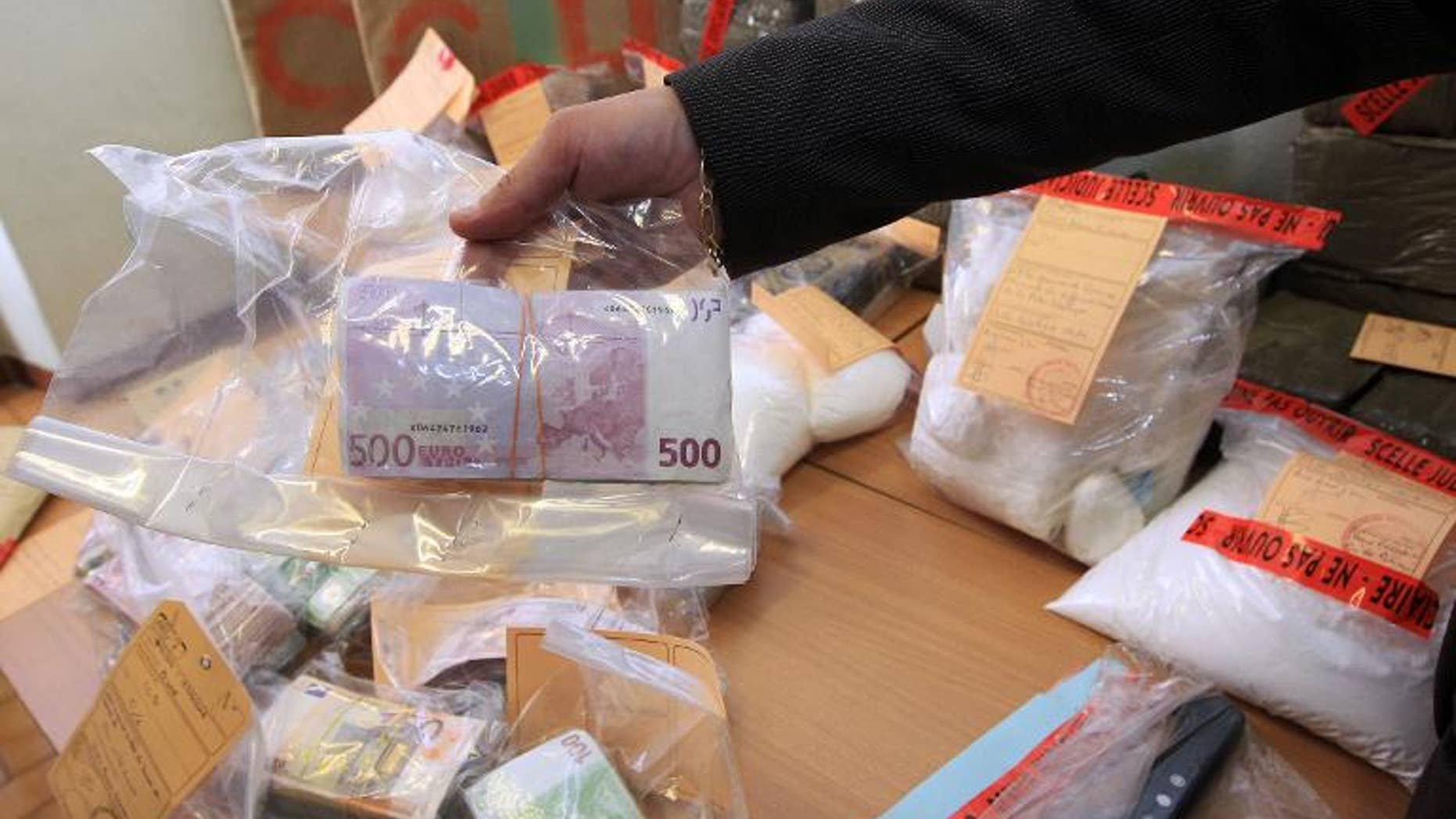 A police officer presents a bundle of cash sized with cocaine, heroin and cannabis on September 17, 2013 in Nice, France