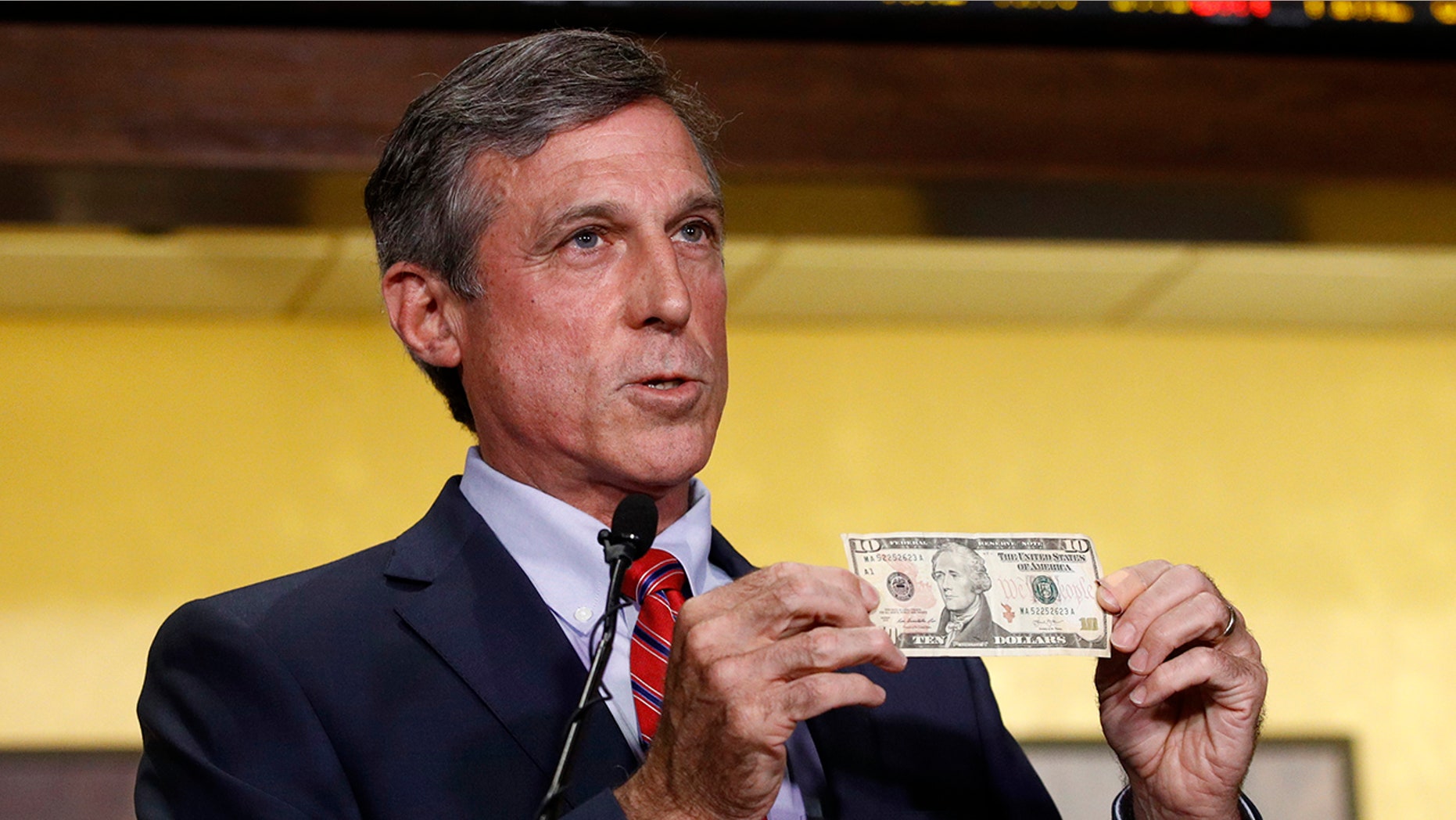 Delaware Gov. John Carney displays a ten dollar bill before using it to place a bet on a baseball game between the Chicago Cubs and the Philadelphia Phillies.