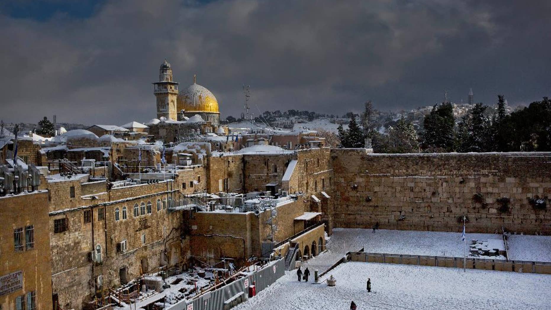 FILE - In this Dec. 13, 2013 file photo, the Western Wall, right, and the gilded Dome of the Rock, among the holiest sites for Jews and Muslims, are covered in snow. Two Palestinians stormed a Jerusalem synagogue on Tuesday, Nov. 18, 2014 attacking worshippers praying inside with knives, axes and guns, and killing four people before they were killed in a shootout with police, officials said. (AP Photo/Dusan Vranic, File)