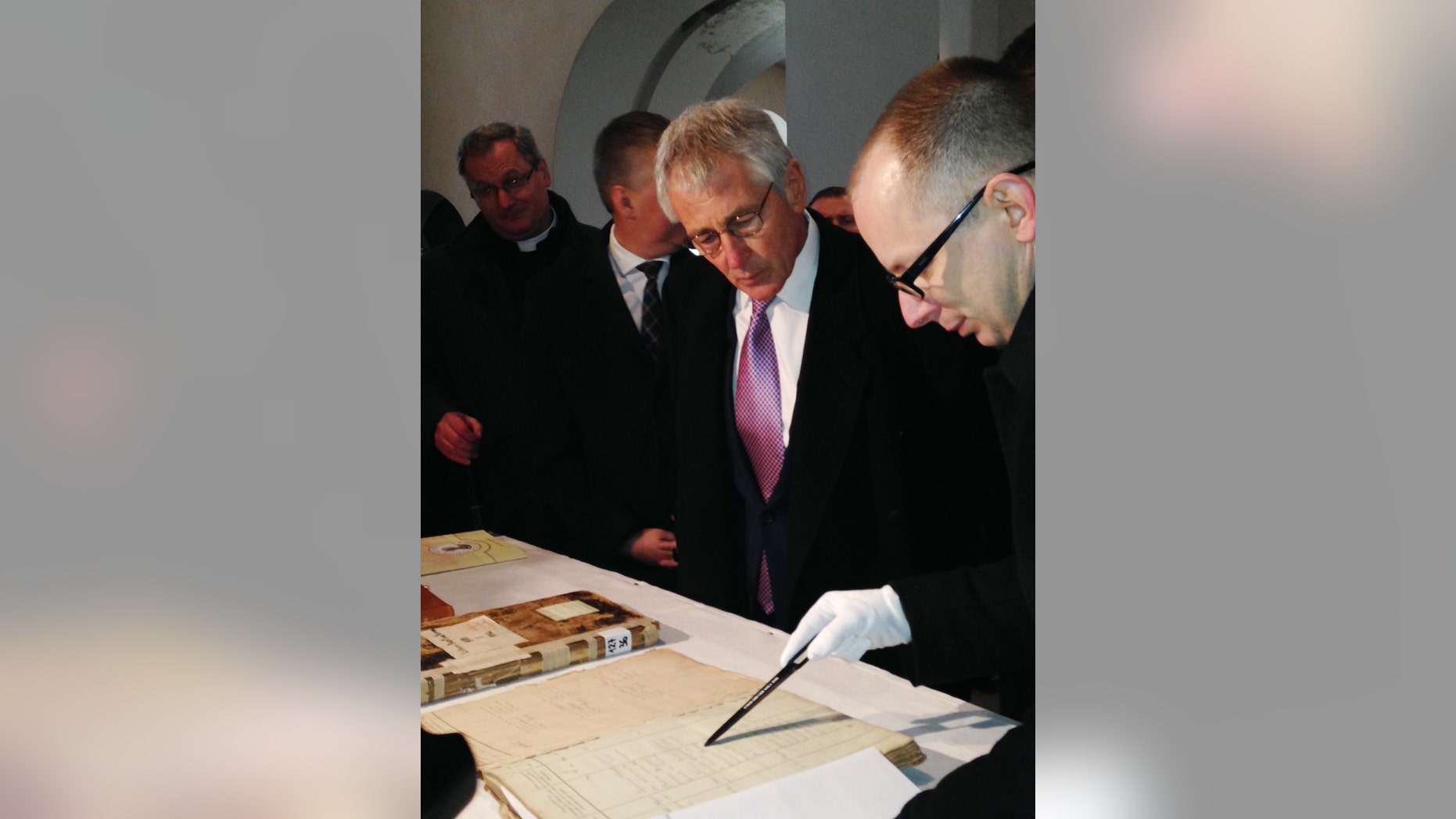 U.S. Defense Secretary Chuck Hagel, center, examines the original marriage certificate of his maternal grandmother's parents at the Dabrowka Church in Kiszkow, Poland, Friday, Jan. 31, 2014. Dabrowka Church is located on the same site where his maternal grandmother's parents were married in 1882. The original church burned down in the 1920's and was later rebuilt. (AP Photo/Robert Burns)