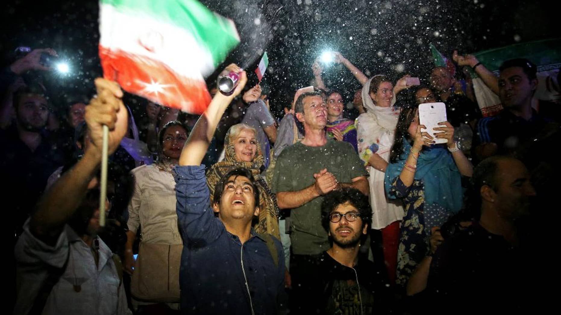A group of jubilant Iranians cheer and spray artificial snow during street celebrations following a landmark nuclear deal, in Tehran, Iran, Tuesday, July 14, 2015. After long, fractious negotiations, world powers and Iran struck an historic deal Tuesday to curb Iran's nuclear program in exchange for billions of dollars in relief from international sanctions - an agreement aimed at averting the threat of a nuclear-armed Iran and another U.S. military intervention in the Middle East. (AP Photo/Ebrahim Noroozi)
