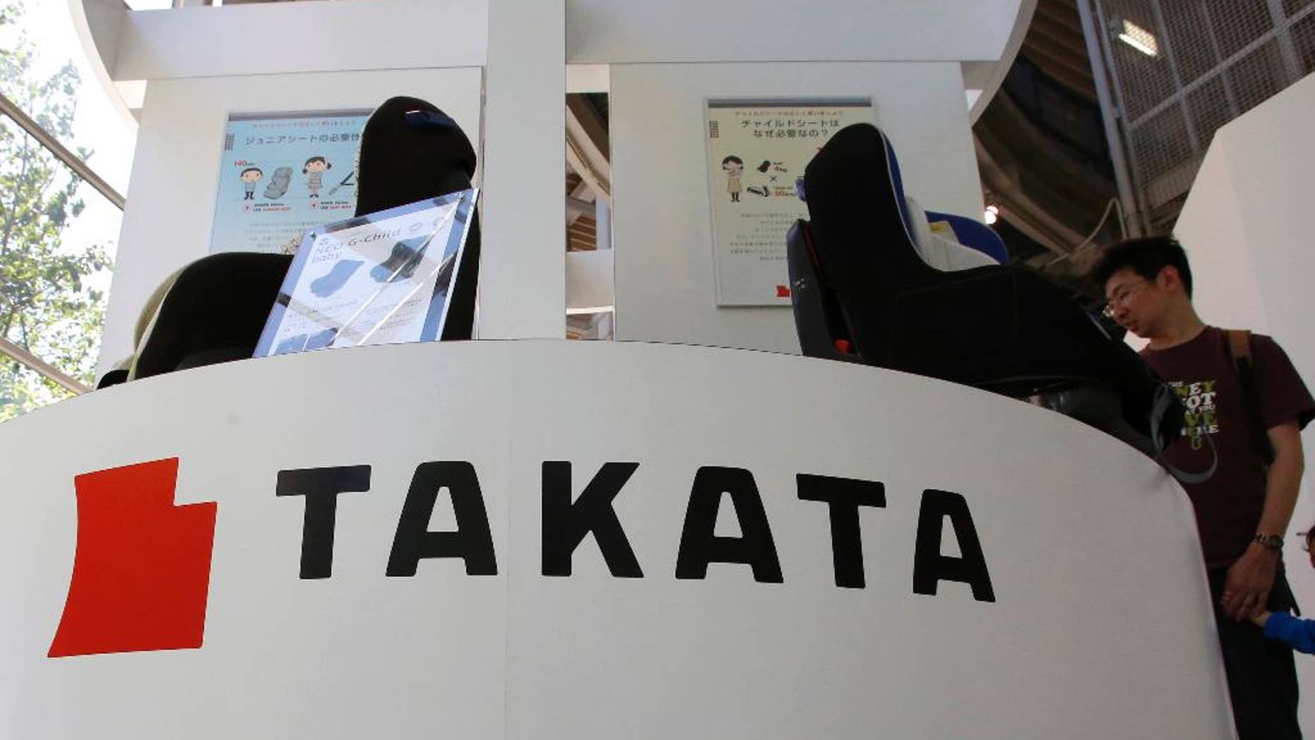 FILE - In this May 4, 2016 file photo, visitors look at child seats, manufactured and displayed by Takata Corp. at an automaker's showroom in Tokyo. Money-losing Japanese air bag maker Takata Corp. hired financial advisory and asset management firm Lazard Thursday, May 26 to help tackle financial problems and massive recalls. (AP Photo/Shizuo Kambayashi, File)
