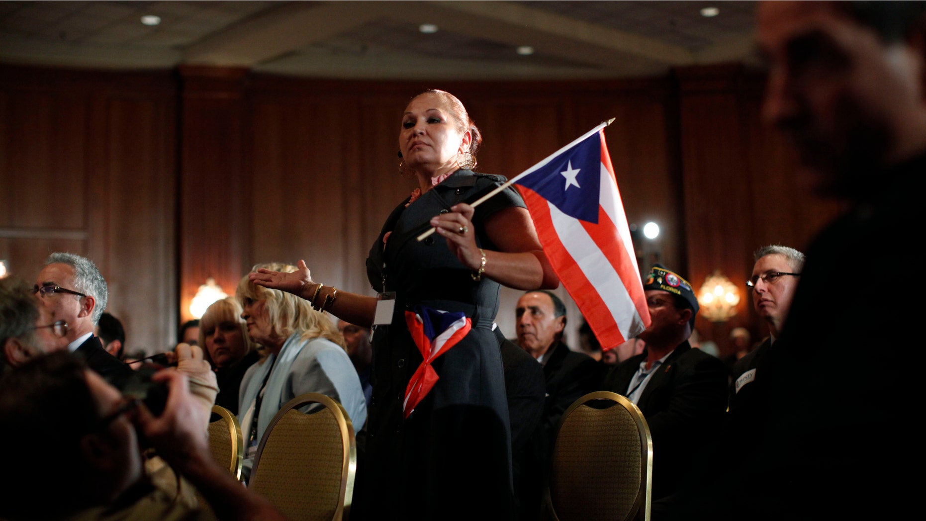 Elizabeth Cuevas-Neunder holds a Puerto Rican flag and asks Republican presidential candidate former House Speaker Newt Gingrich a question during the Hispanic Leadership Network conference at the Doral Golf Resort and Spa, Friday, Jan. 27, 2012, in Miami, Fla. Romney and Gingrich square off over immigration and other issues as they look to woo Hispanics a day after a feisty, final debate before Tuesdays Florida primary. (AP Photo/Matt Rourke)