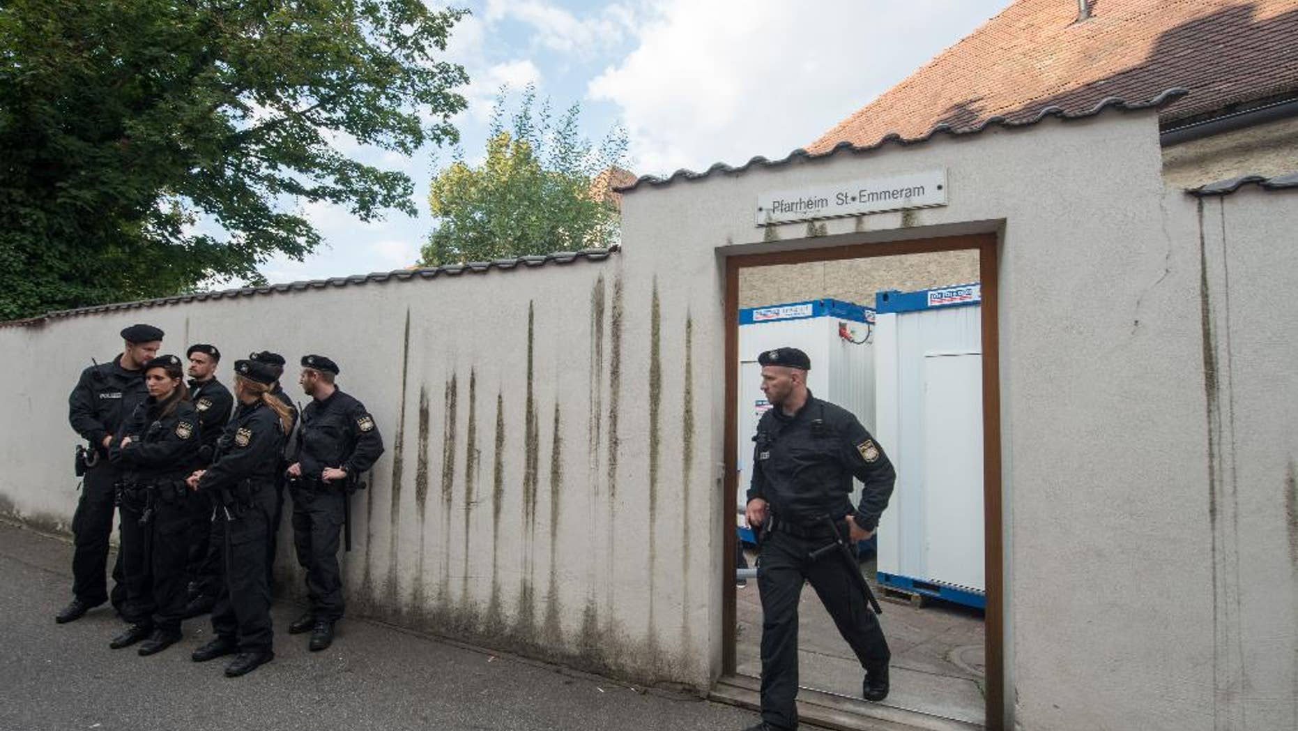 In this Aug. 8, 2016 picture police officers standing in front of the parish hall of St. Emmeram where refugees were living in Regensburg, Germany.The Roman Catholic diocese in Bavaria says it has ended a five-week protest at a church building by migrants from the Balkans. Some 50 migrants started camping out at Regensburg Cathedral early last month, demanding the right to stay in Germany and protesting the Balkan nations' designation as safe countries. A few days later, most moved to a vicarage across town. The diocese said the last 16 people were persuaded to leave Monday by police. (Armin Weigel/dpa via AP)